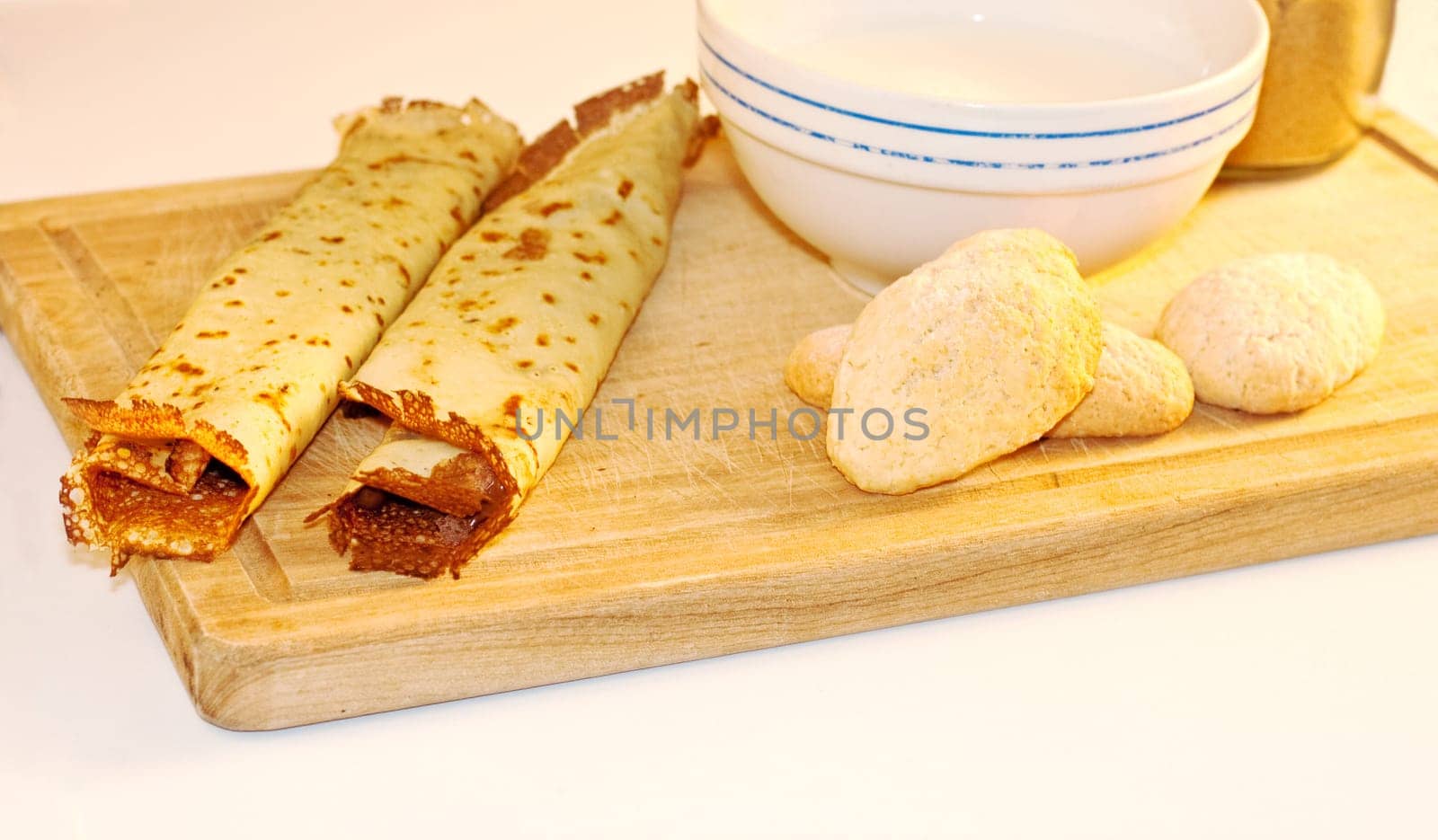 Crepes, cookies and milk on cutting board