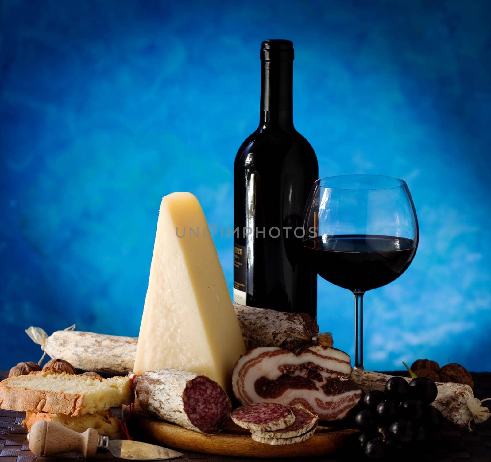 Salumi armiggiano cheese, and glass of red wine on purple background