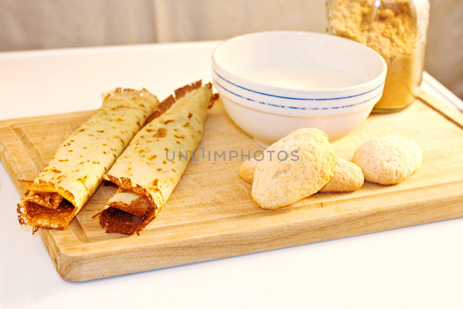 Crepes, cookies and milk on cutting board