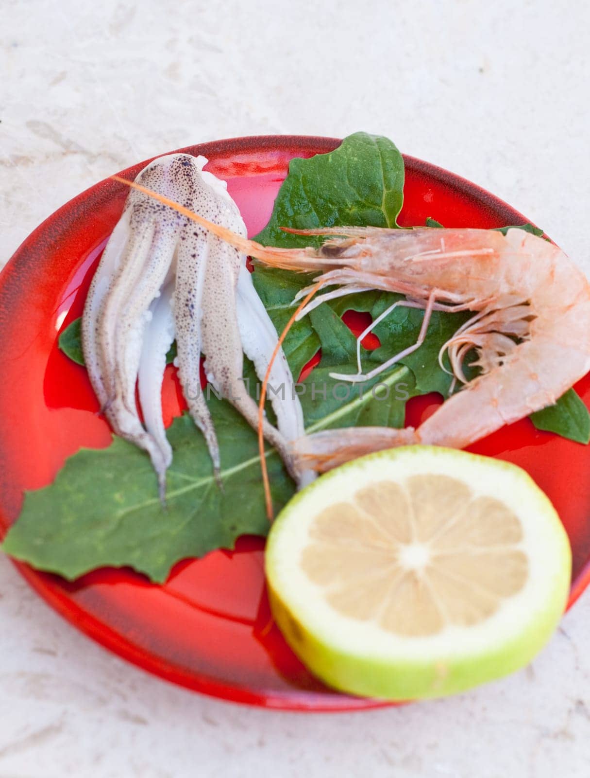 Shrimp, cuttlefish and lemon inside a red saucer