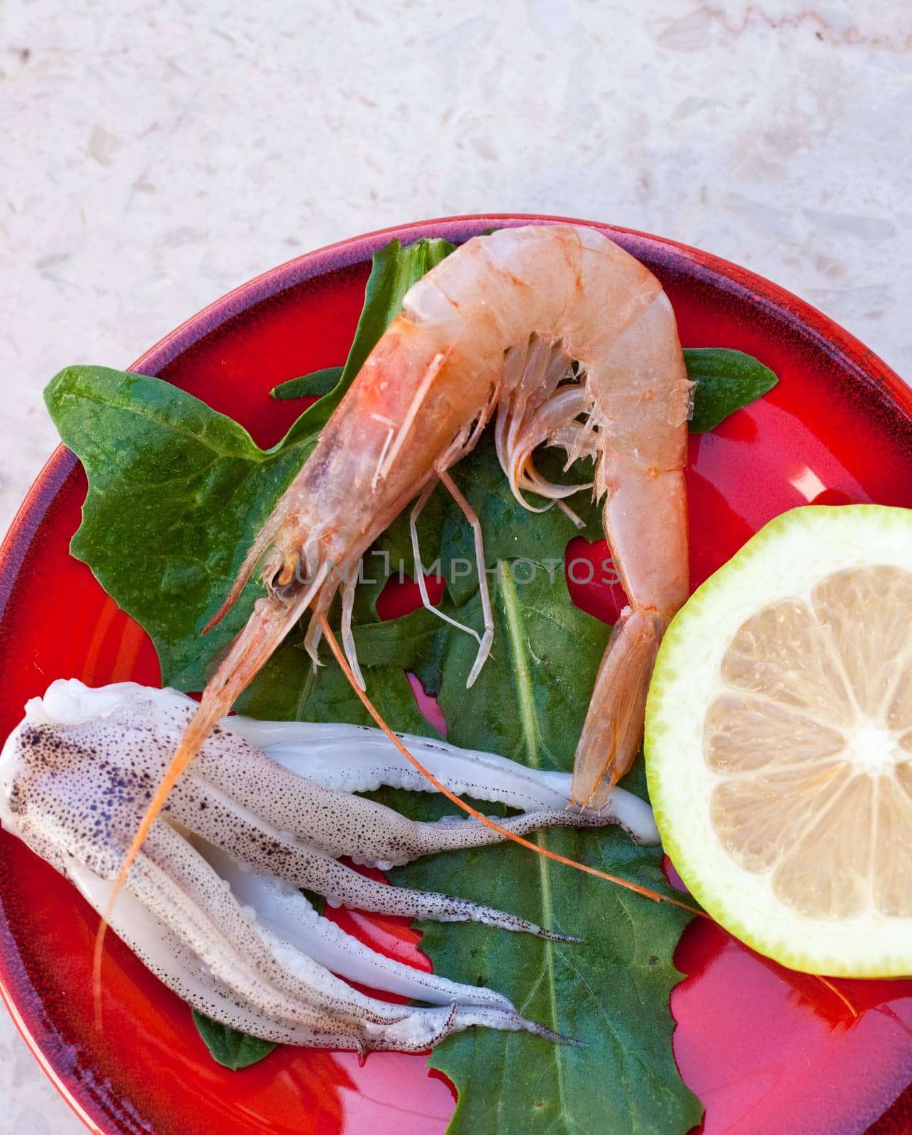 Shrimp, cuttlefish and lemon inside a red saucer