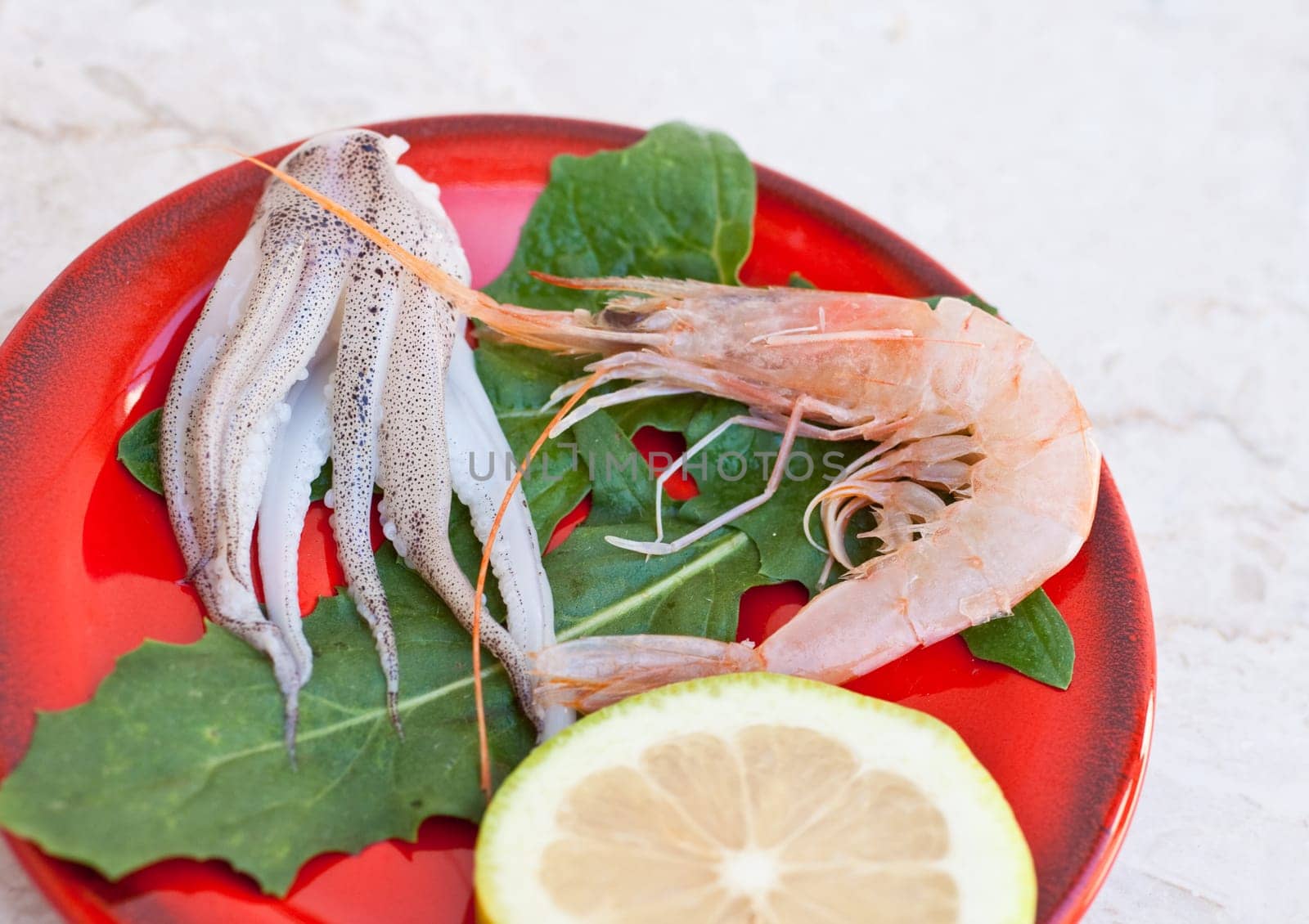 Shrimp, cuttlefish and lemon inside a red saucer