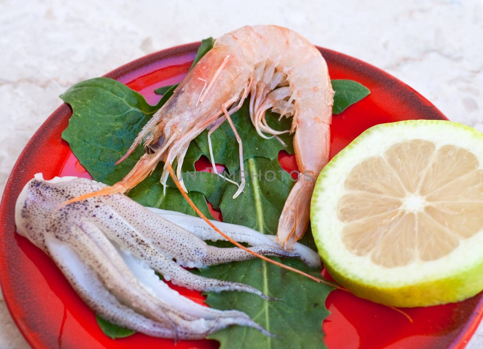 Shrimp, cuttlefish and lemon inside a red saucer