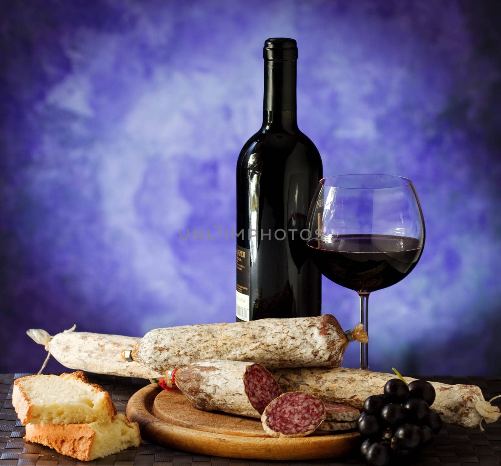 Salumi armiggiano cheese,  and glass of red wine on purple background