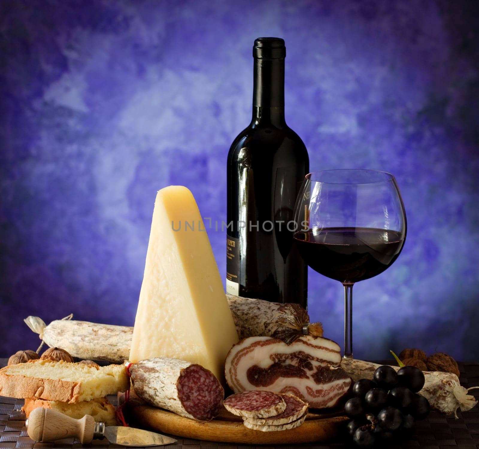 Salumi armiggiano cheese,  and glass of red wine on purple background