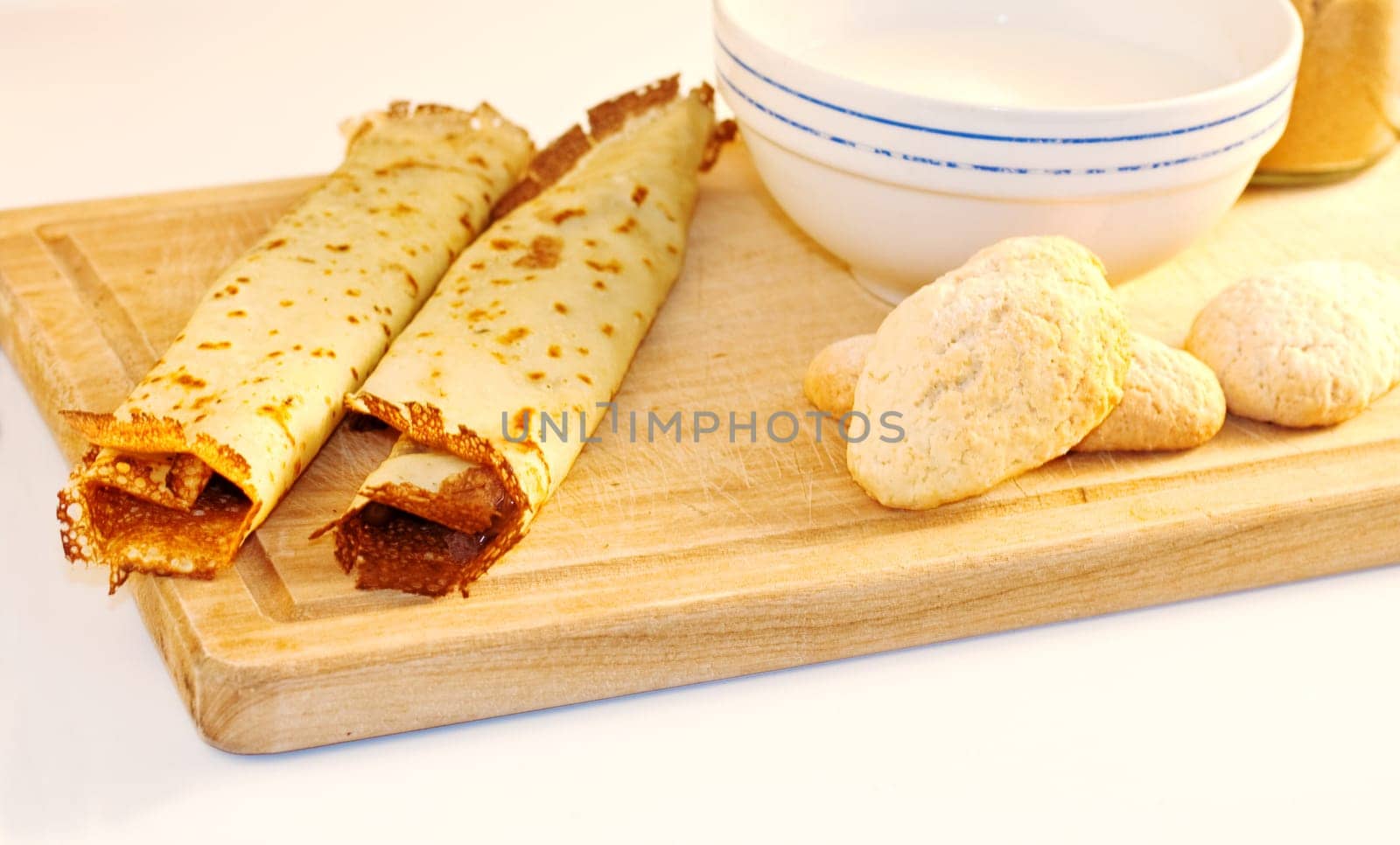 Crepes, cookies and milk on cutting board
