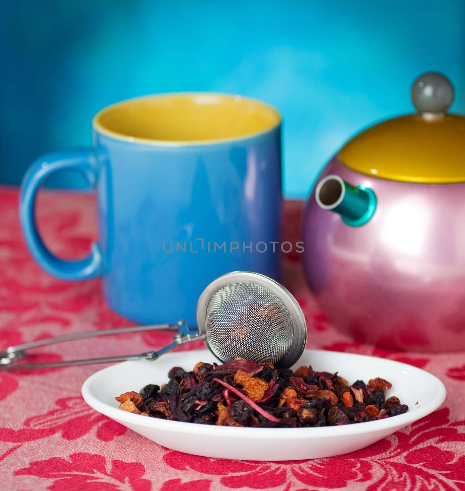 Teapot, cup and herbs on blue background