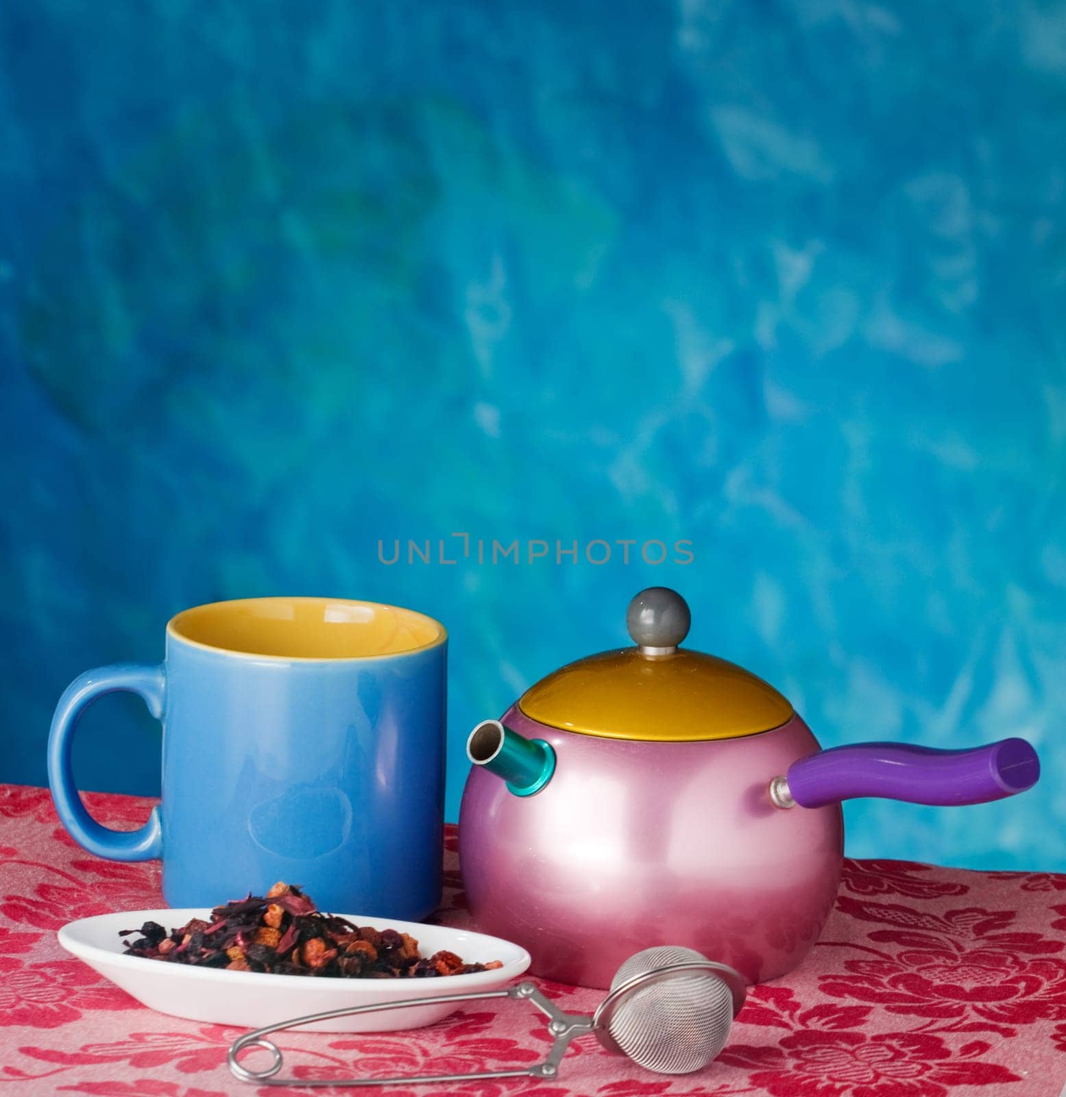 Teapot, cup and herbs on blue background