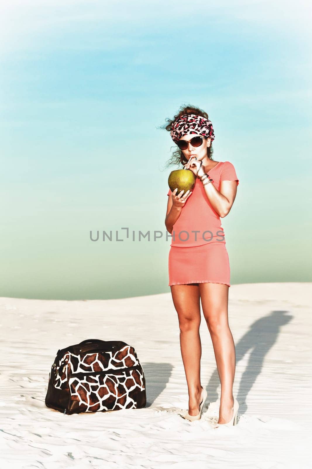 Beautiful woman with coconut in desert