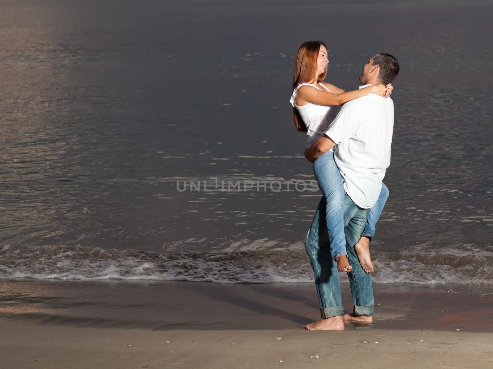 Young couple near the sea at sunrise