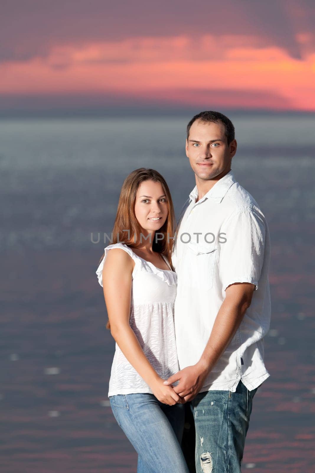 Young couple near the sea at sunrise