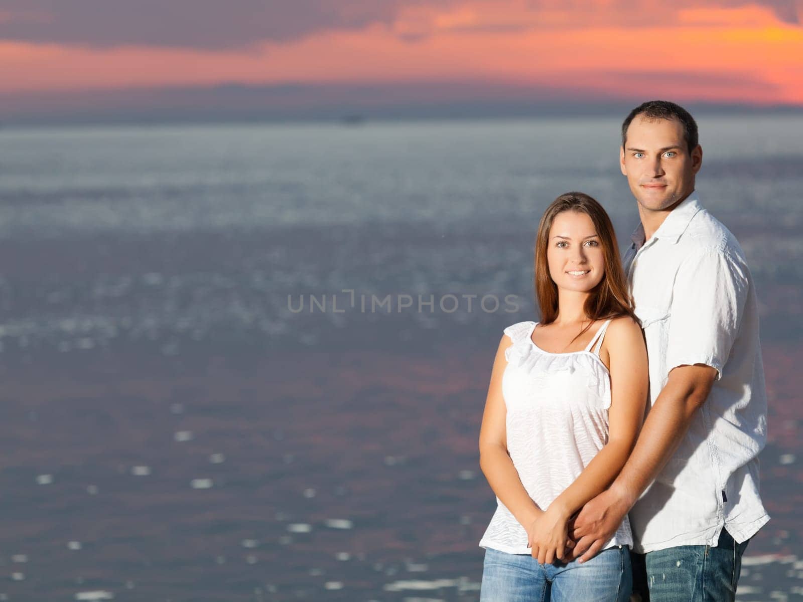 Young couple near the sea at sunrise