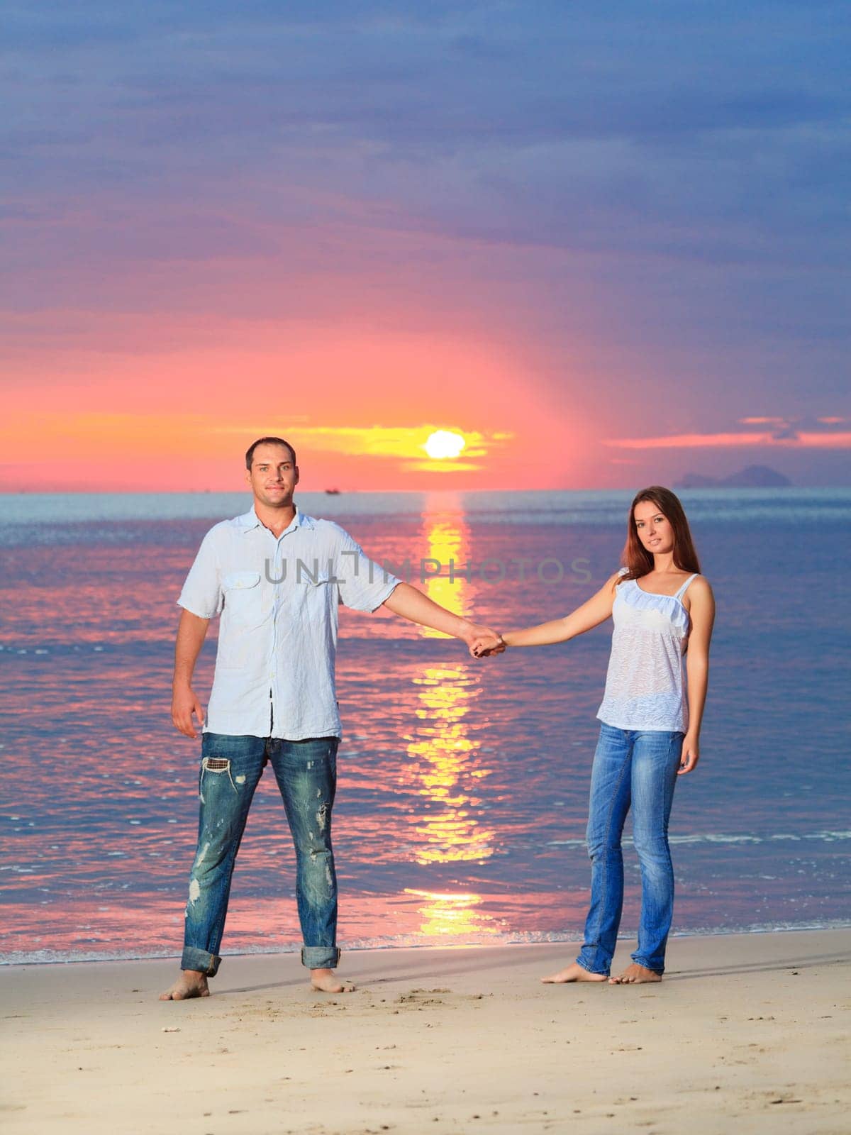 Young couple near the sea at sunrise