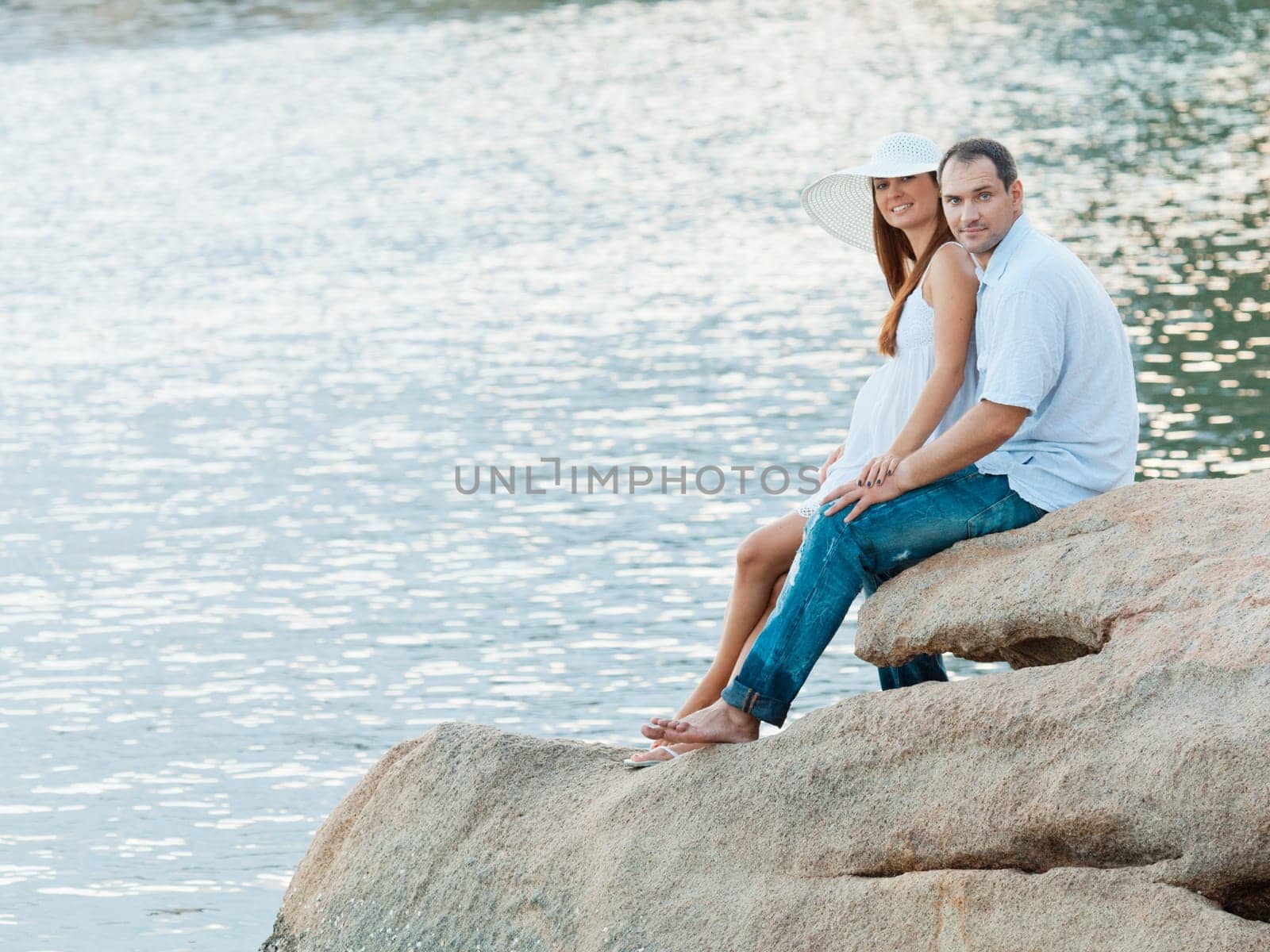 Young couple sitting on the cliff near ocean