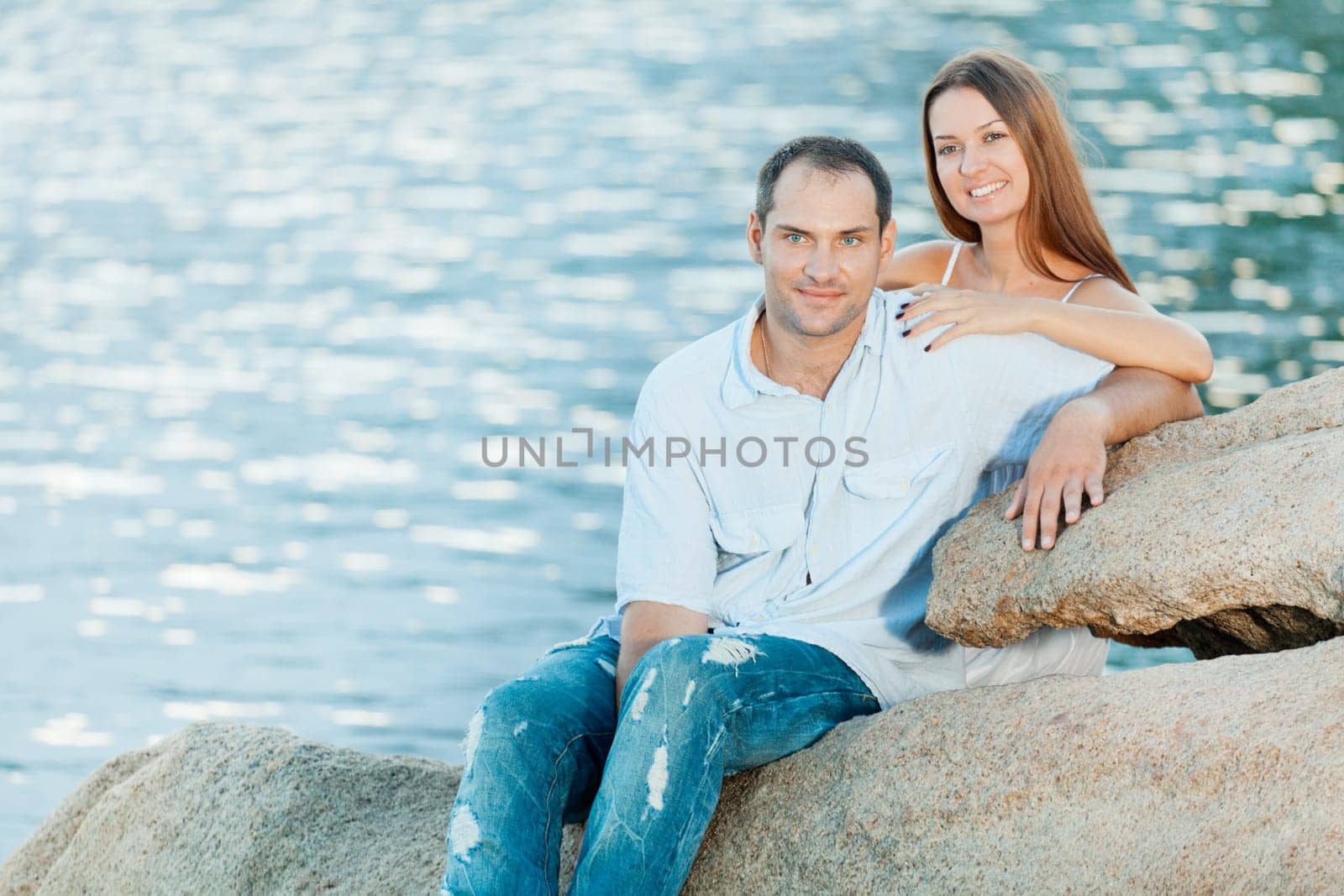 Young couple sitting on the cliff near ocean
