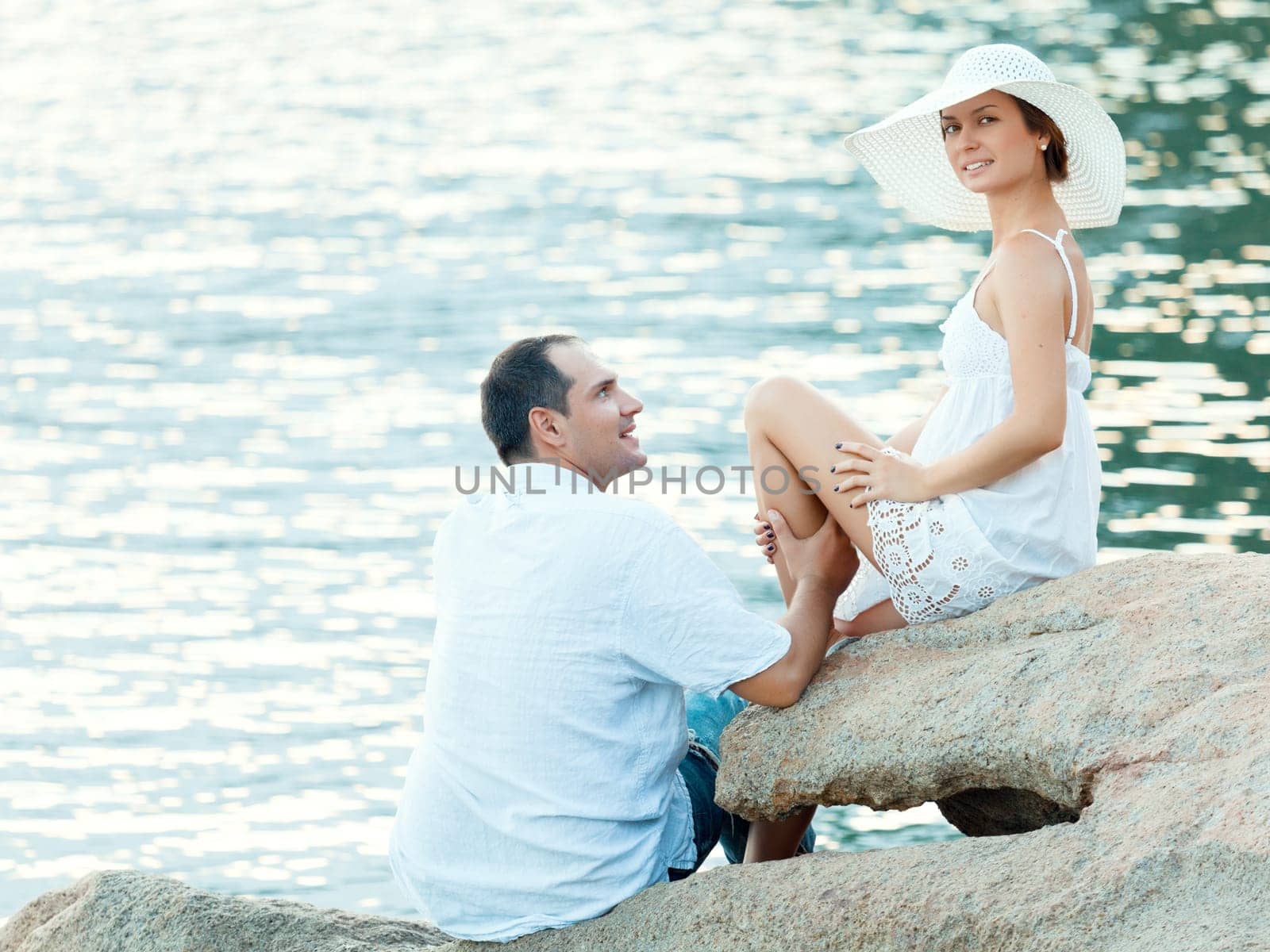 Young couple sitting on the cliff near ocean