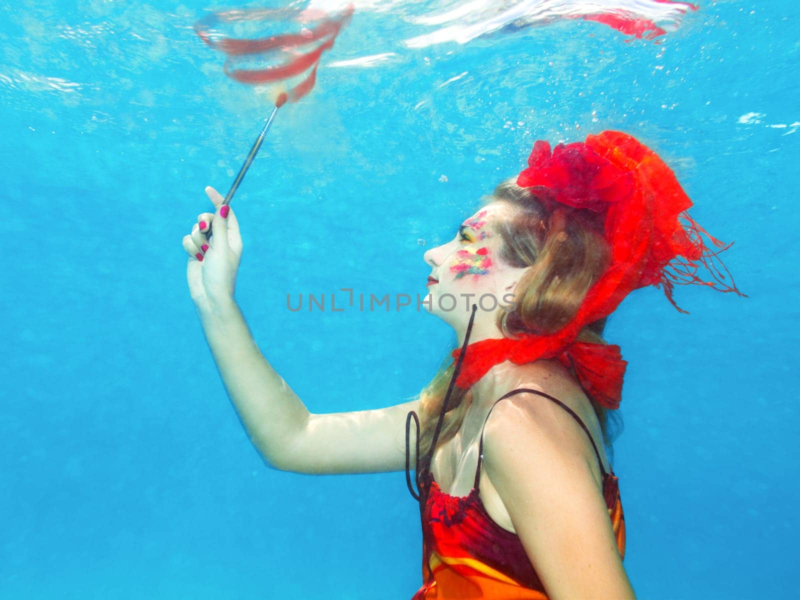 Woman with face art draws. Underwater shot
