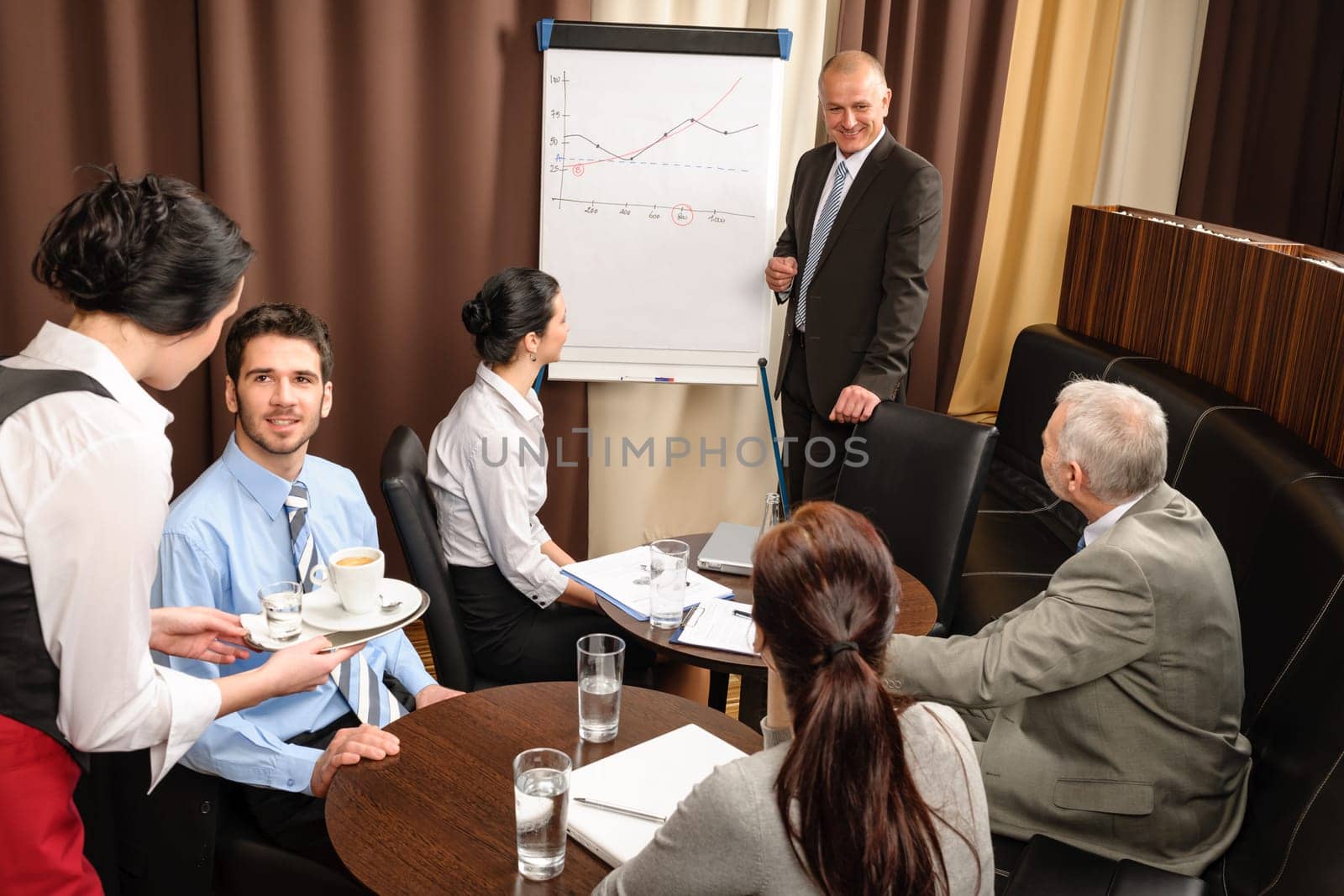 Executive businessman giving presentation on flip-chart to team formalwear