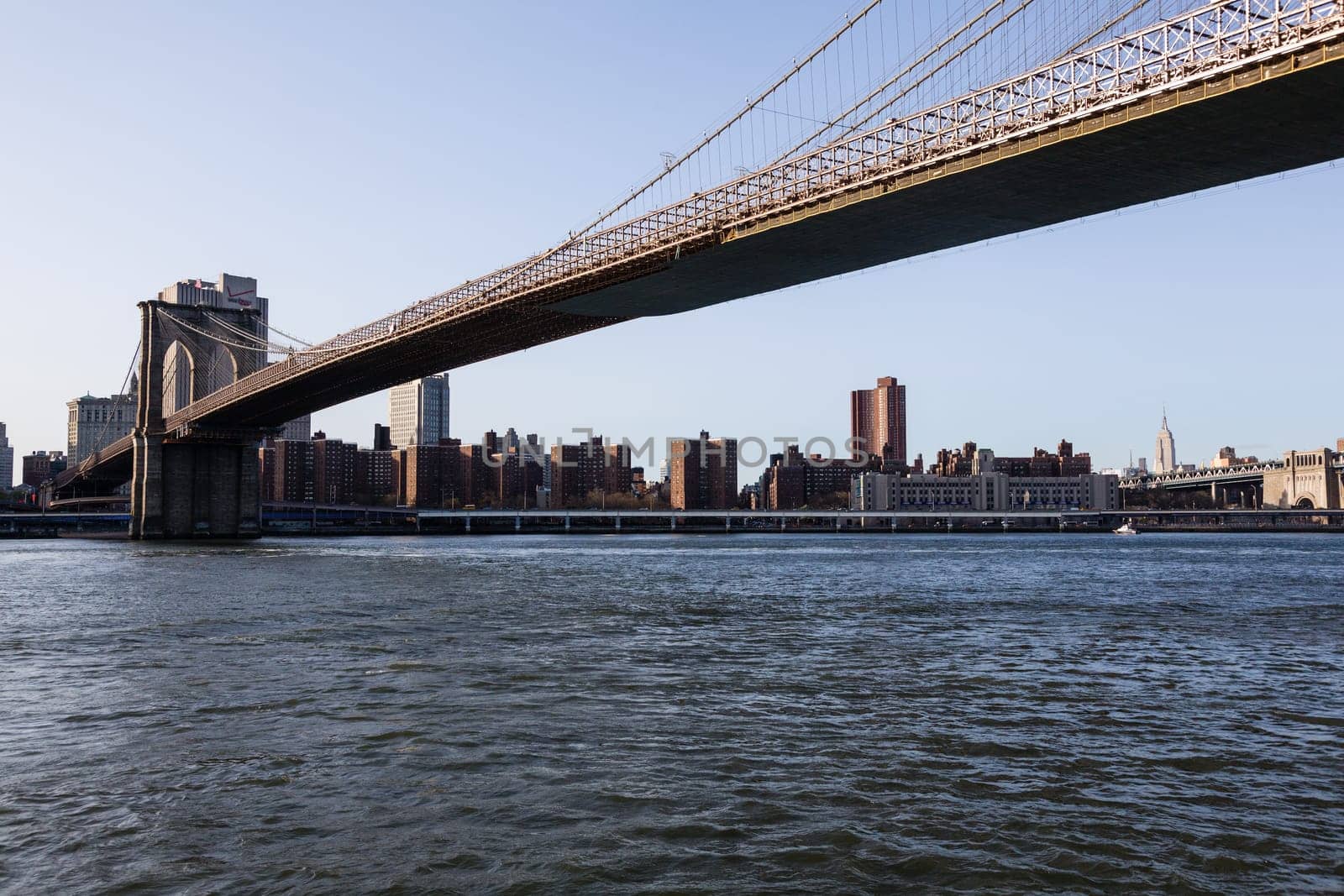 Empire State Tower visible under span of Brooklyn bridge in NY