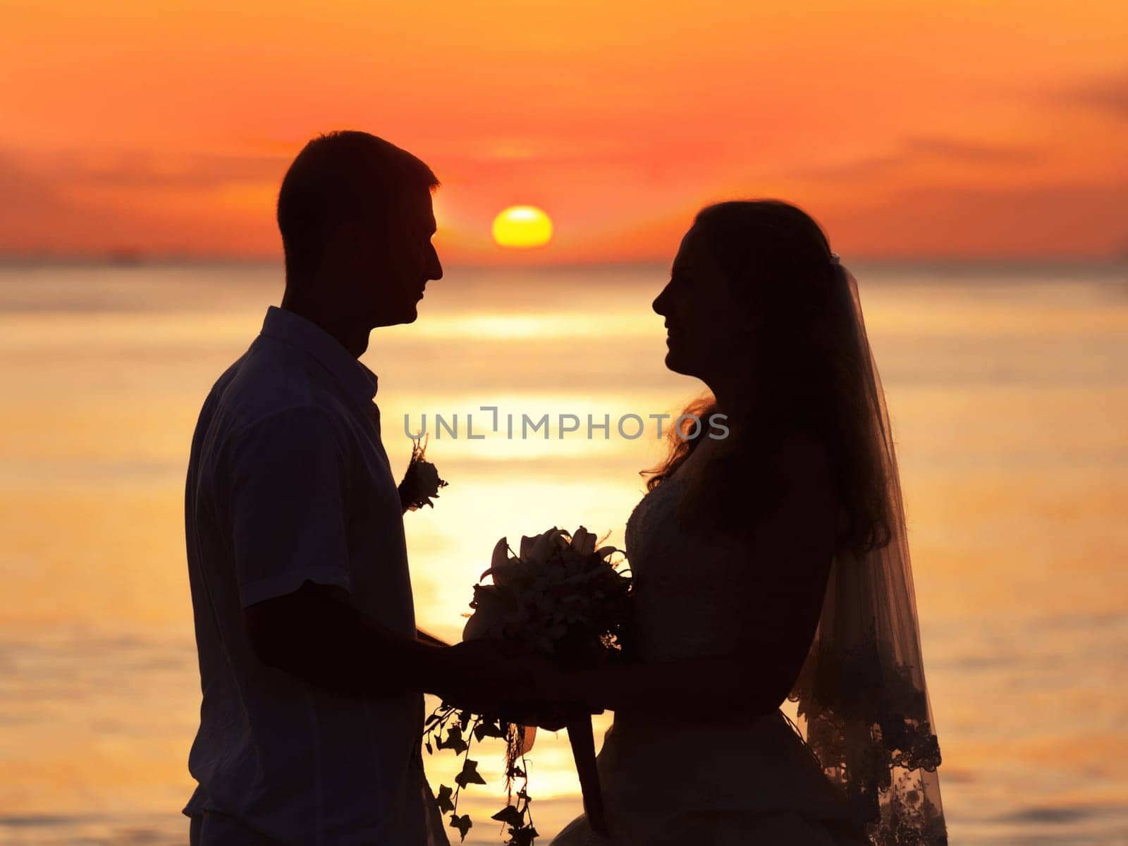Shape of a bride and groom on the beach at sunrise time