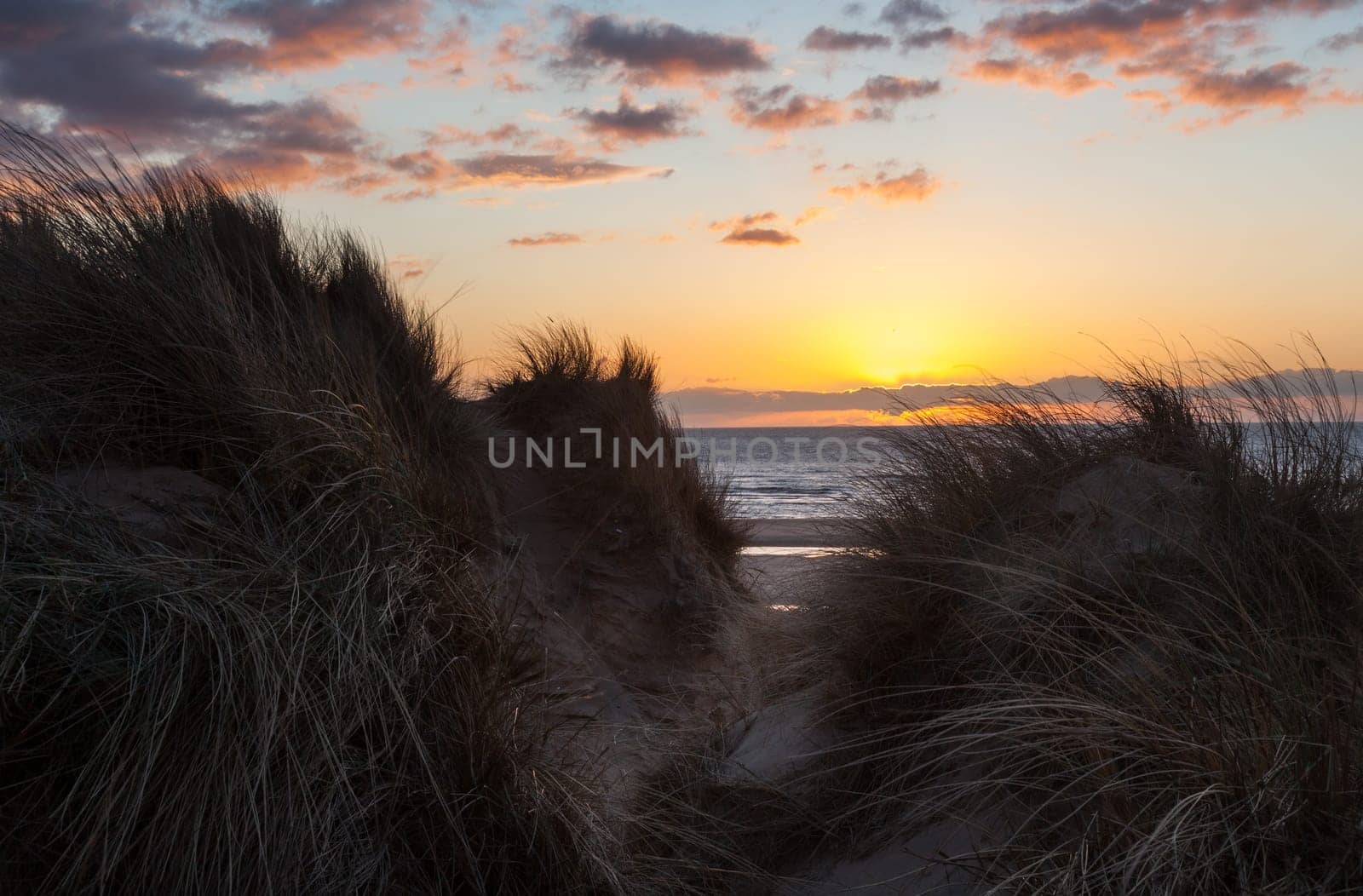 Sun setting over the beach at Formby in England through sand dunes