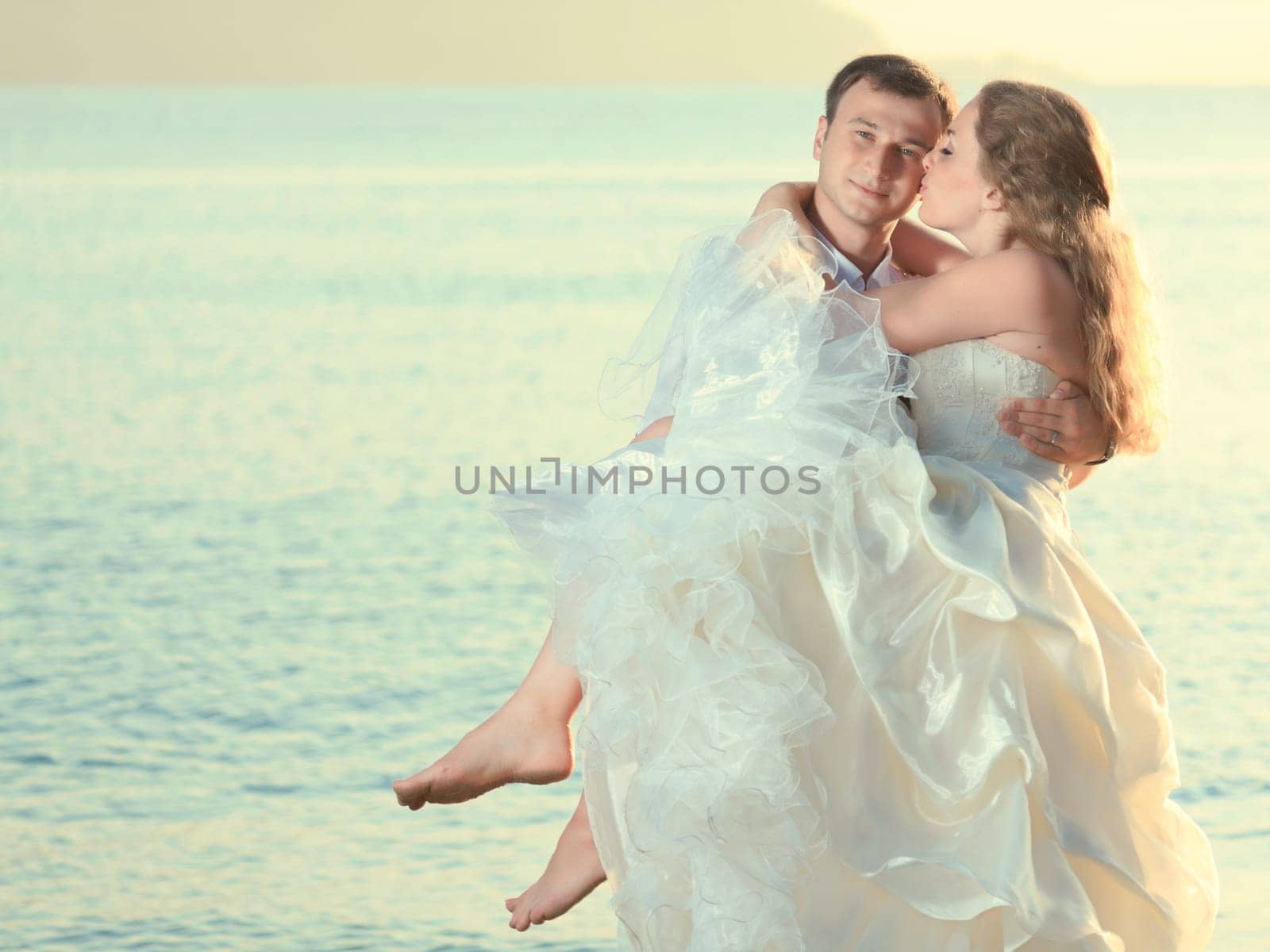 Groom holding up a his bride on the beach