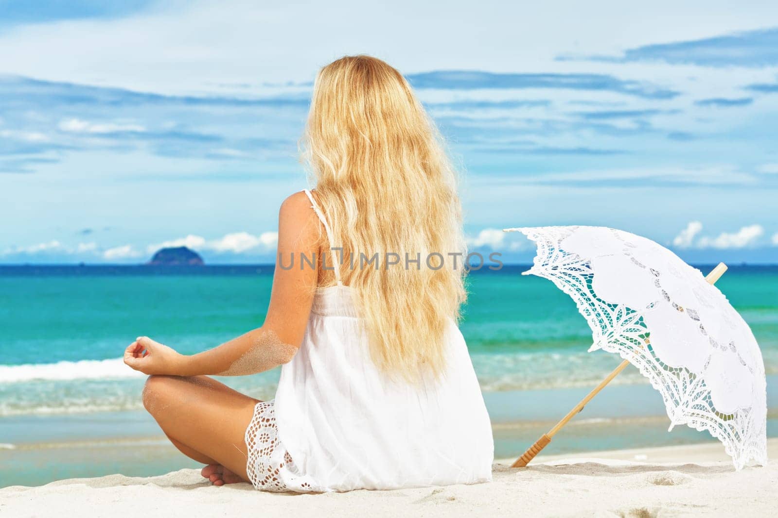 Woman with umbrella meditating on the tropical beach