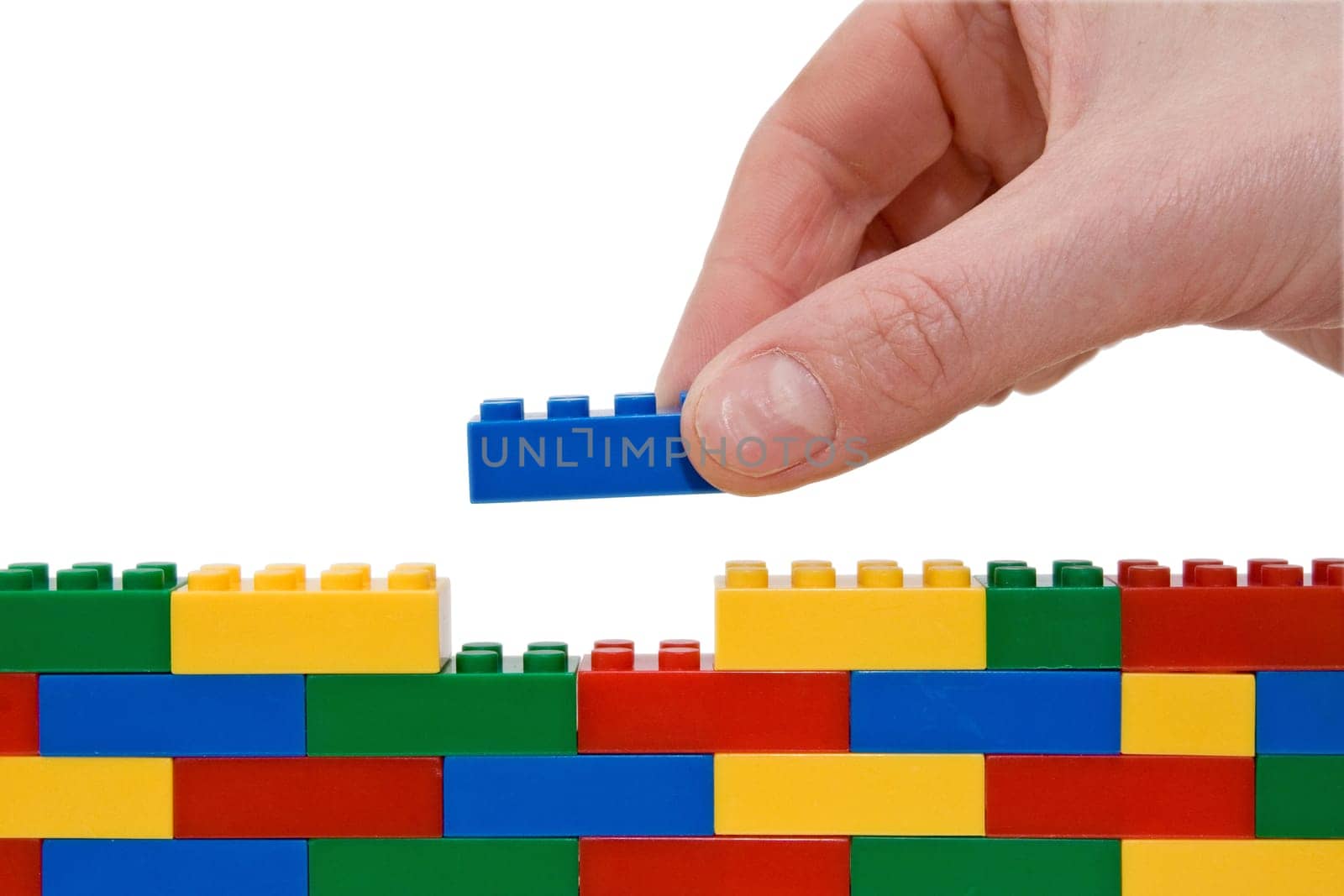 hand building up a wall by stacking up lego