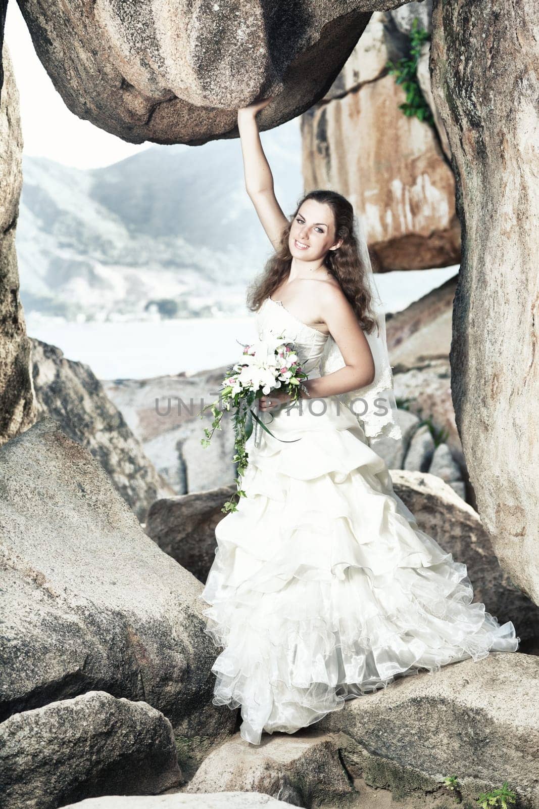 Beautiful bride holding a rock near sea