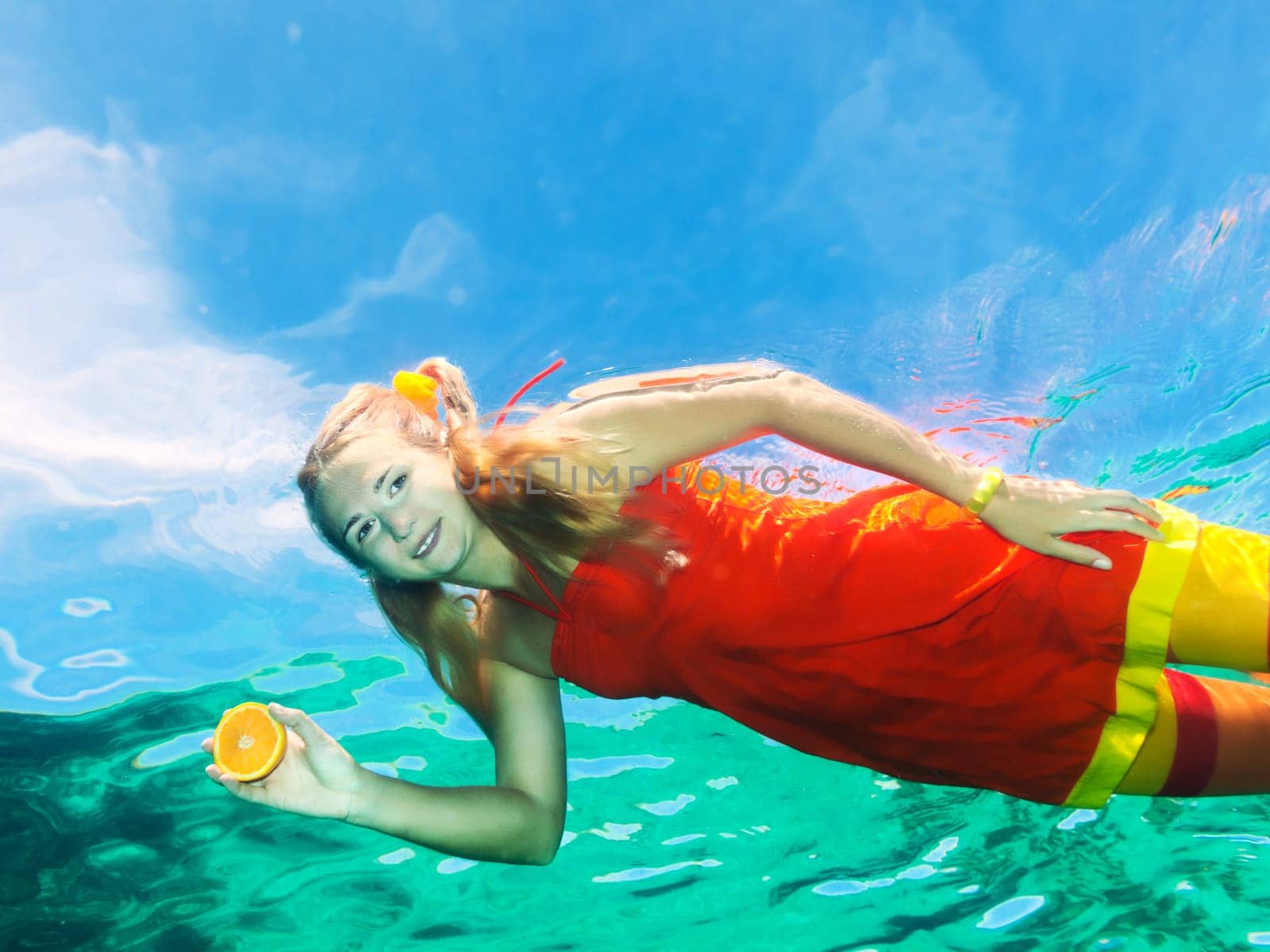 Underwater shot of a funny woman with orange