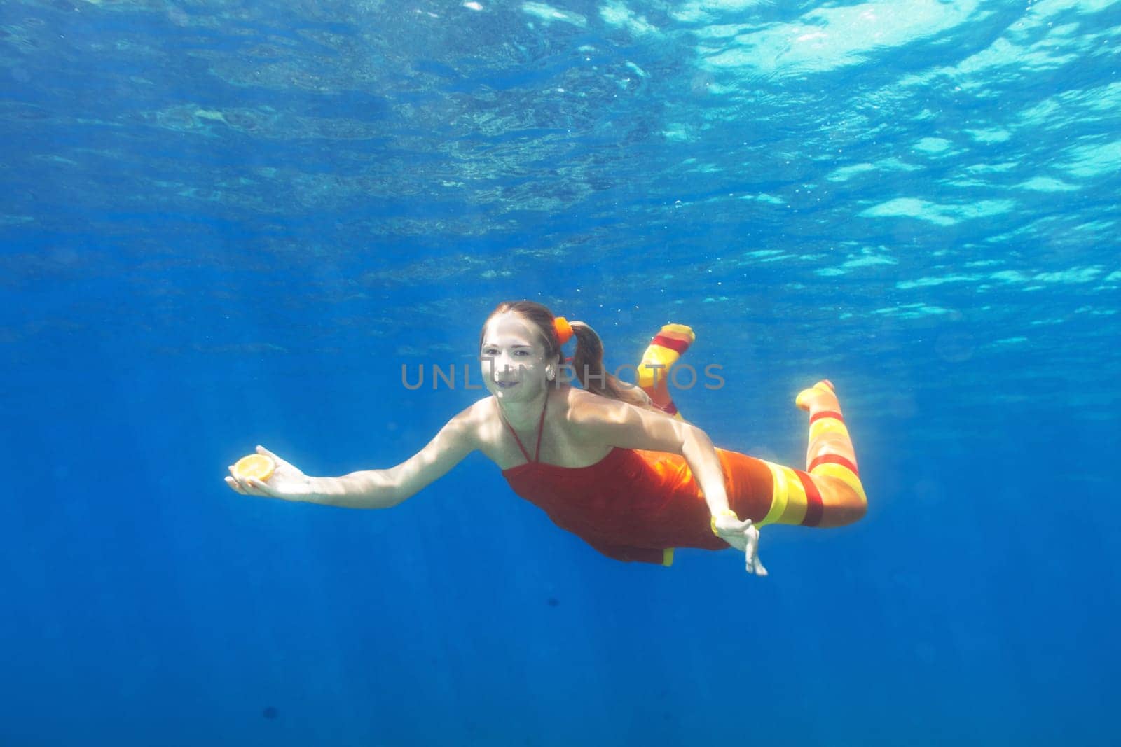Underwater shot of a funny woman with orange