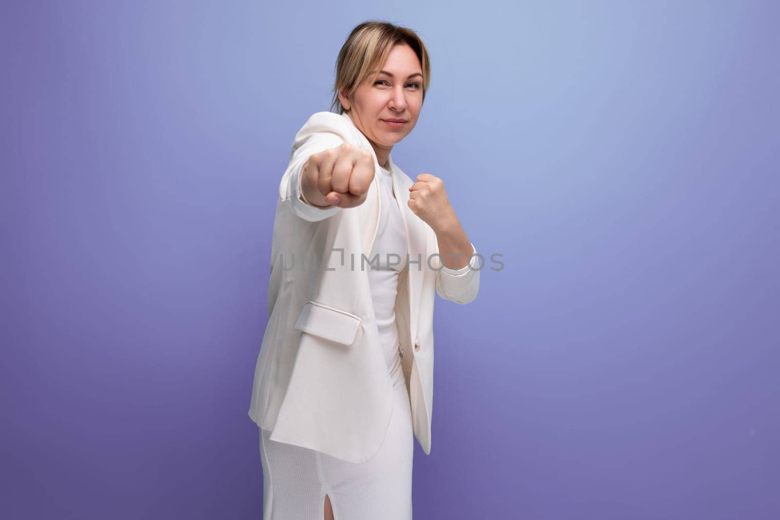 young blond woman dressed in a jacket and dress demonstrates with her hands an advertising offer.