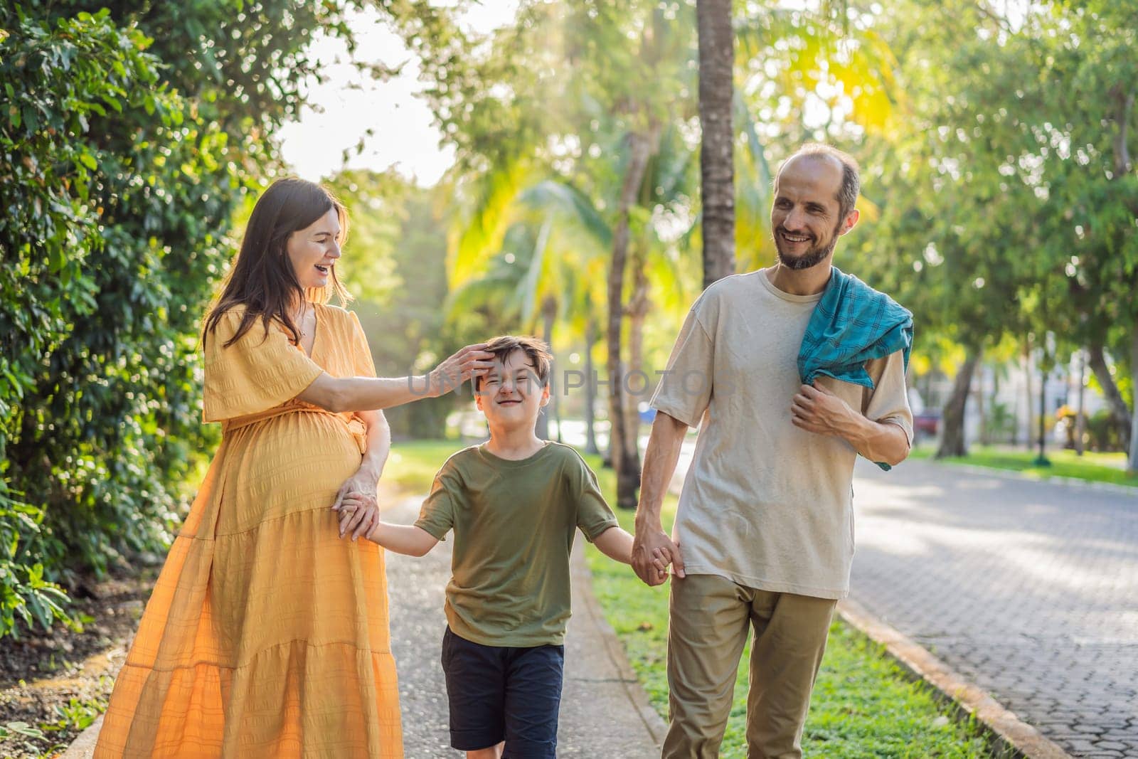 A loving family enjoying a leisurely walk in the park - a radiant pregnant woman after 40, embraced by her husband, and accompanied by their adult teenage son, savoring precious moments together amidst nature's beauty. Pregnancy after 40 concept.