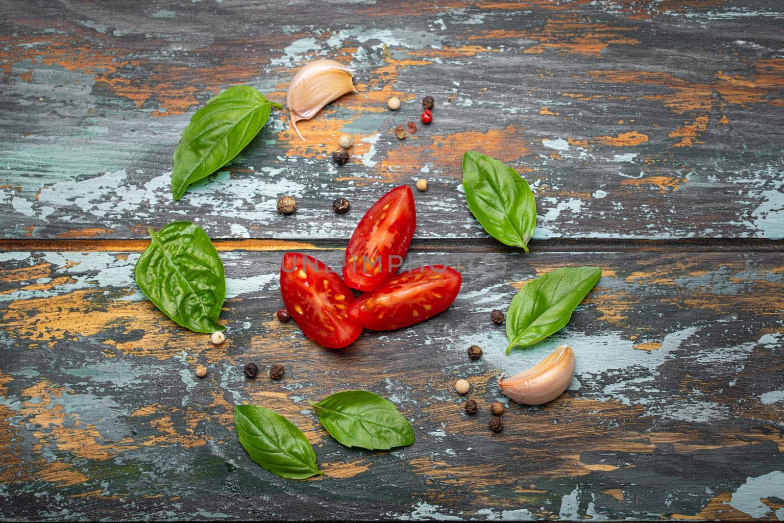 Food cooking border with cherry tomatoes, fresh green basil and garlic cloves top view on rustic colourful wooden background, ingredients for preparing meal, copy space by its_al_dente
