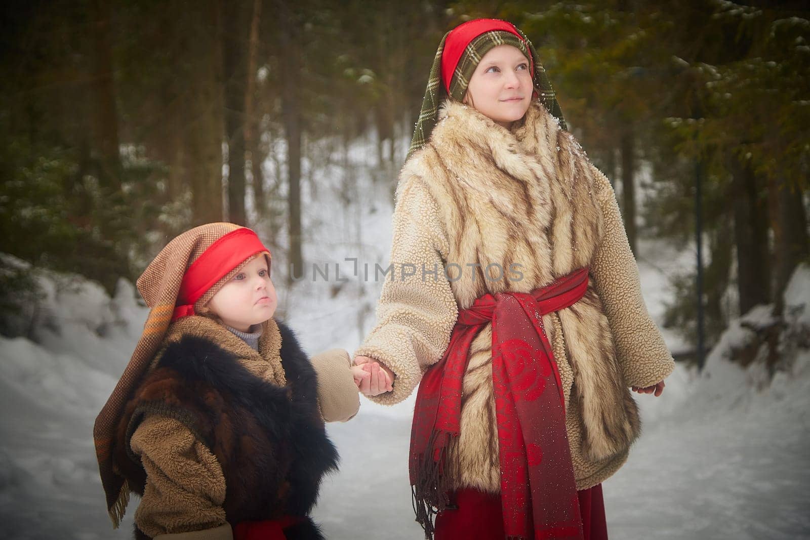 Teen and little girl in thick coat in cold winter day in forest. Medieval peasant sisters collecting firewood. Photoshoot in stile of Christmas fairy tale by keleny
