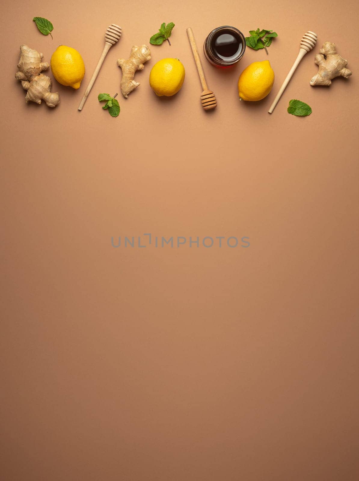 Composition with lemons, mint, ginger, honey in glass jar and honey wooden dippers top view. Food for immunity stimulation and against seasonal flu. Healthy natural remedies to boost immune system.