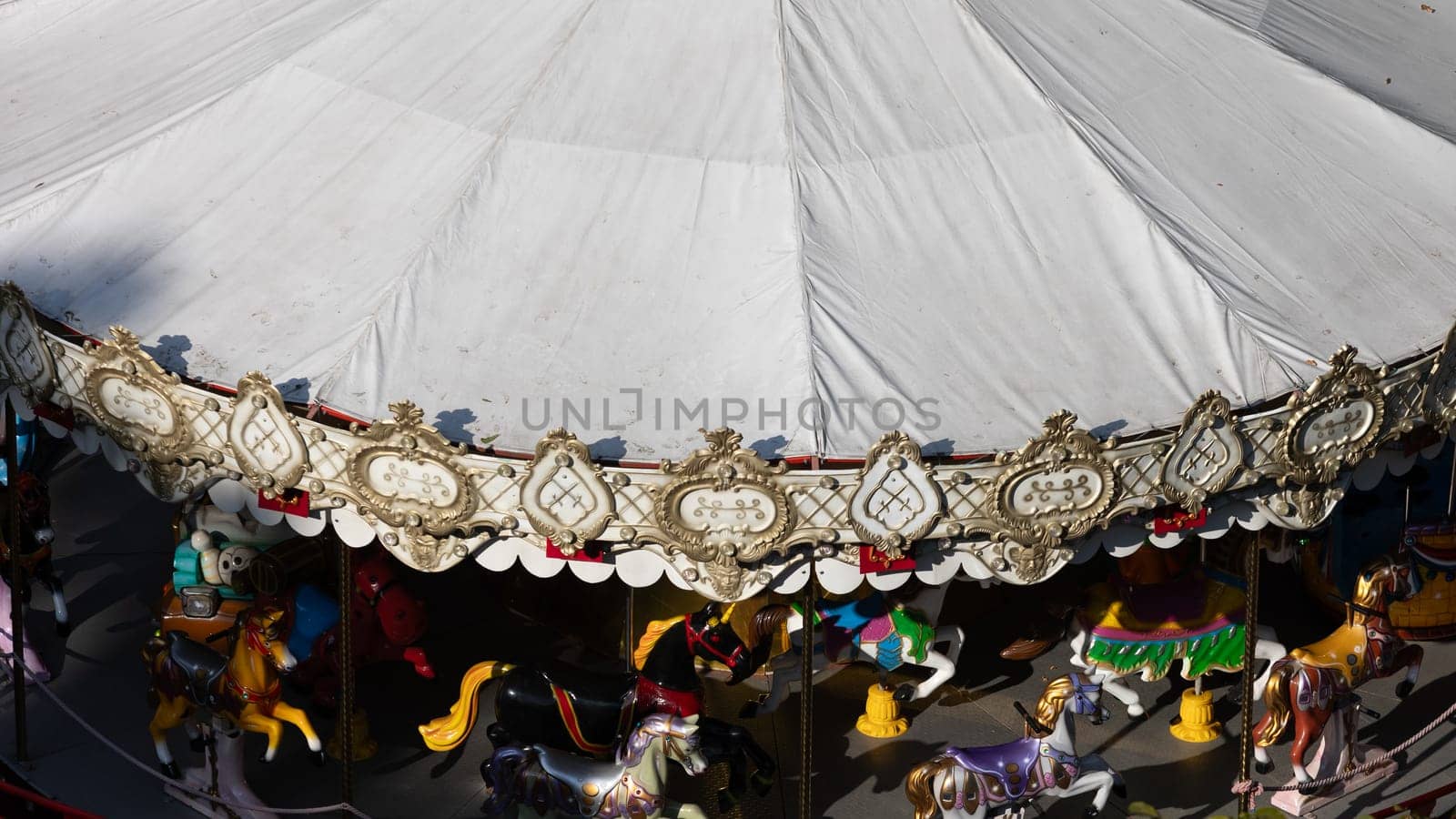 Old fashioned merry-go-round fairground attraction with horses, cart and a sledge. Top view