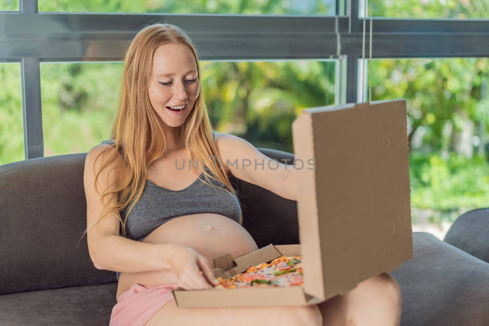 A pregnant woman enjoys a slice of pizza, savoring a moment of indulgence while satisfying her craving for a delightful, comforting treat. Excited Pregnant Young Lady Enjoying Pizza Holding Biting Tasty Slice Posing With Carton Box. Junk Food Lover Eating Italian Pizza. Unhealthy Nutrition Cheat Meal.