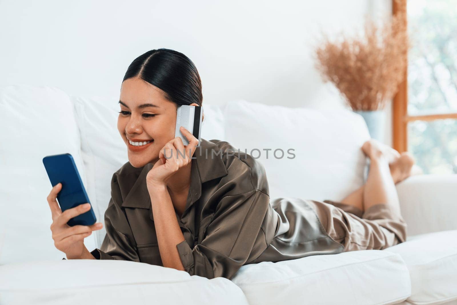 Young happy Asian woman buy product by online shopping at home while ordering items from the internet with credit card online payment protected by uttermost cyber security from online store platform