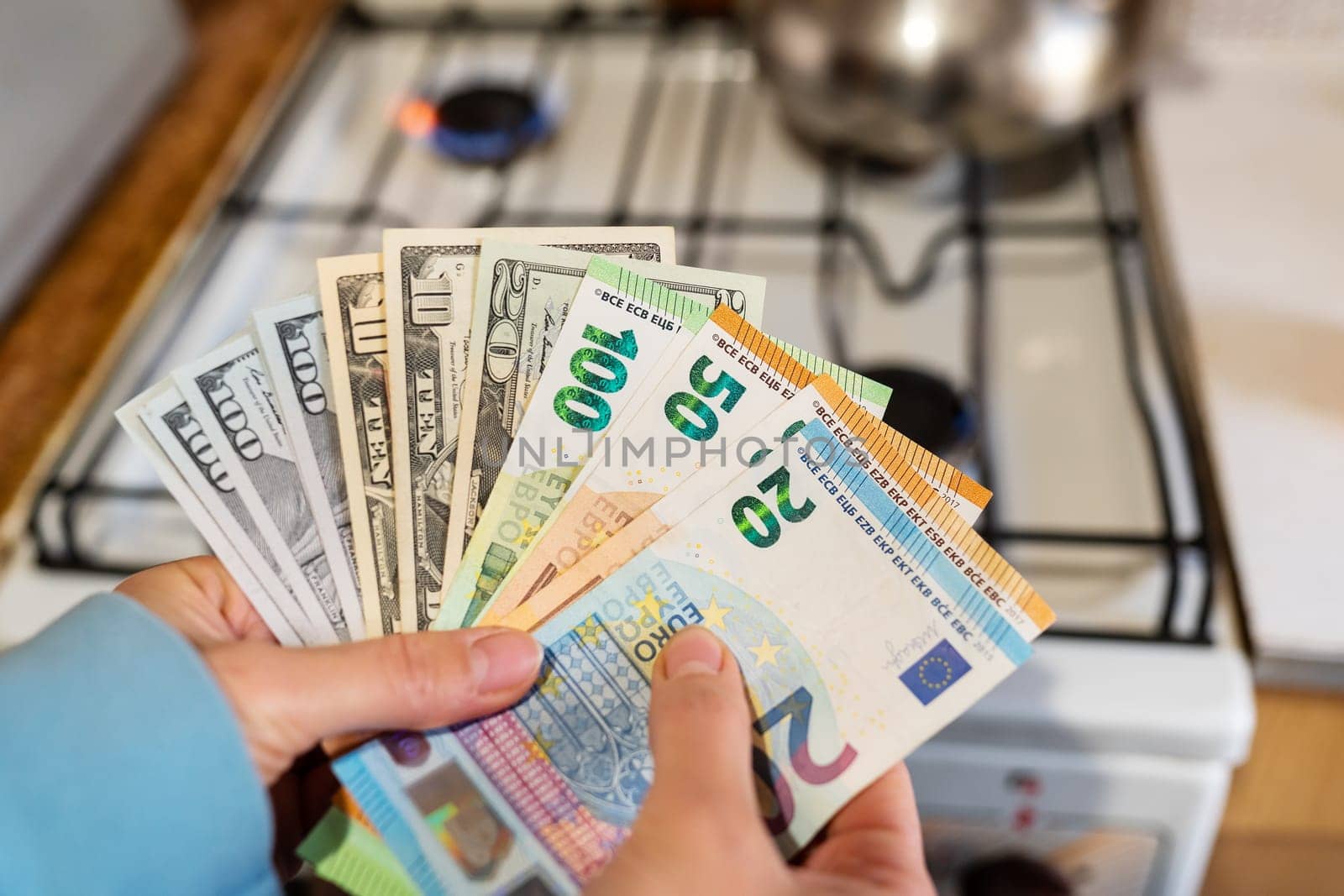 Euro and dollar banknotes on the background of a burning gas burner. Concept of increasing cost of supply, energy crisis. High cost, the price of gas