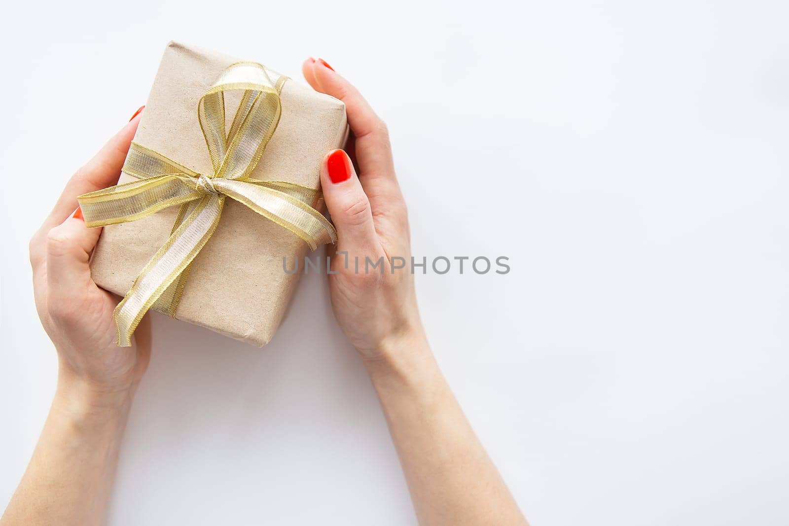 The girl holds a gift with a golden ribbon in her hands on a white background. Time to wrap presents. The concept of surprise, surprise loved ones