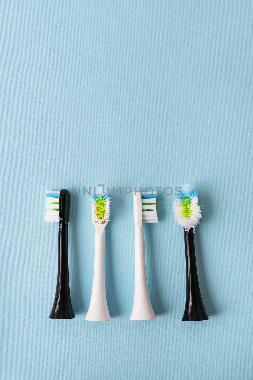 Modern electric toothbrush on a blue background, it's time to change the brush - old and new brush attachment. Hygiene concept for daily oral care