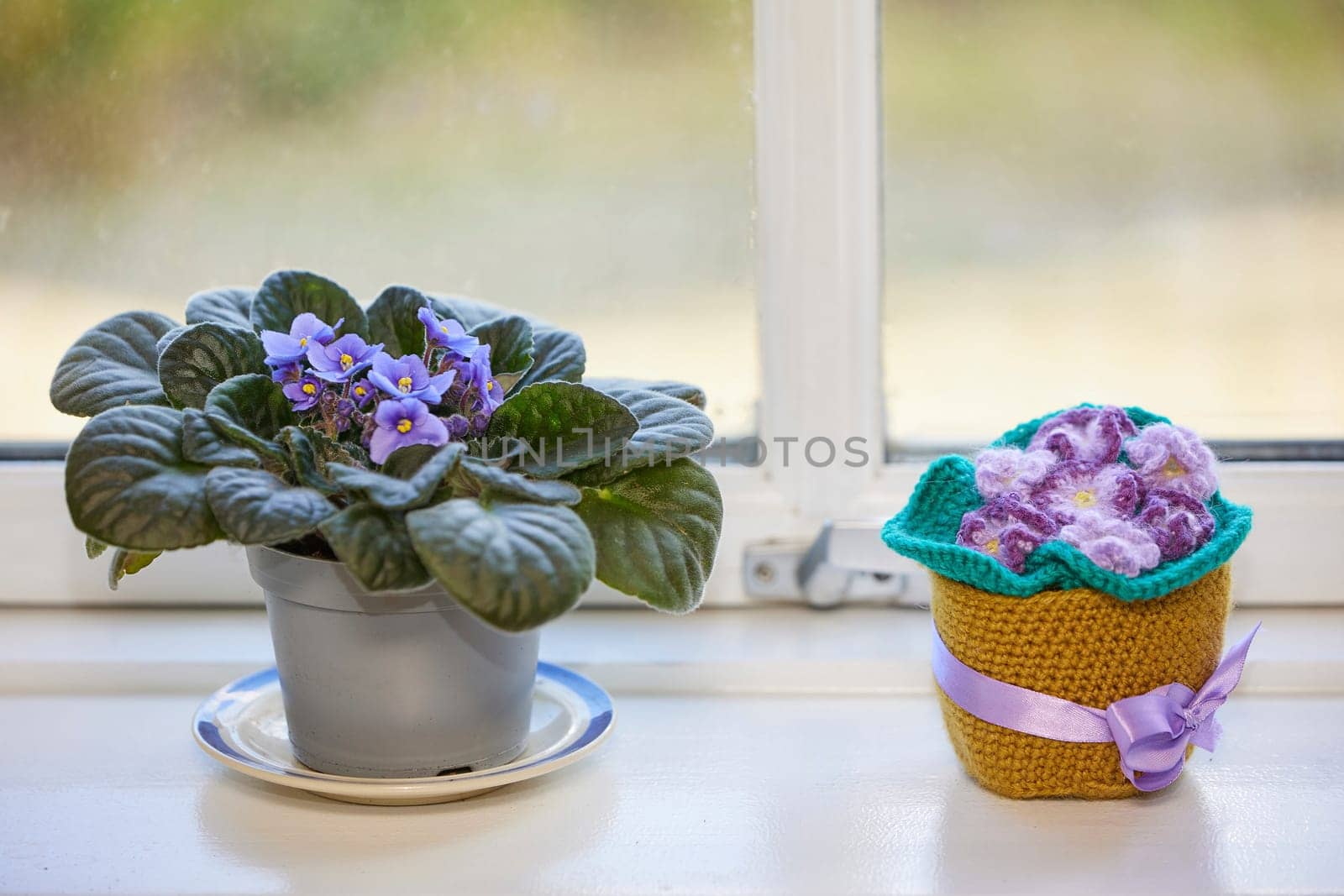 Cute knitted violet toy on the windowsill.