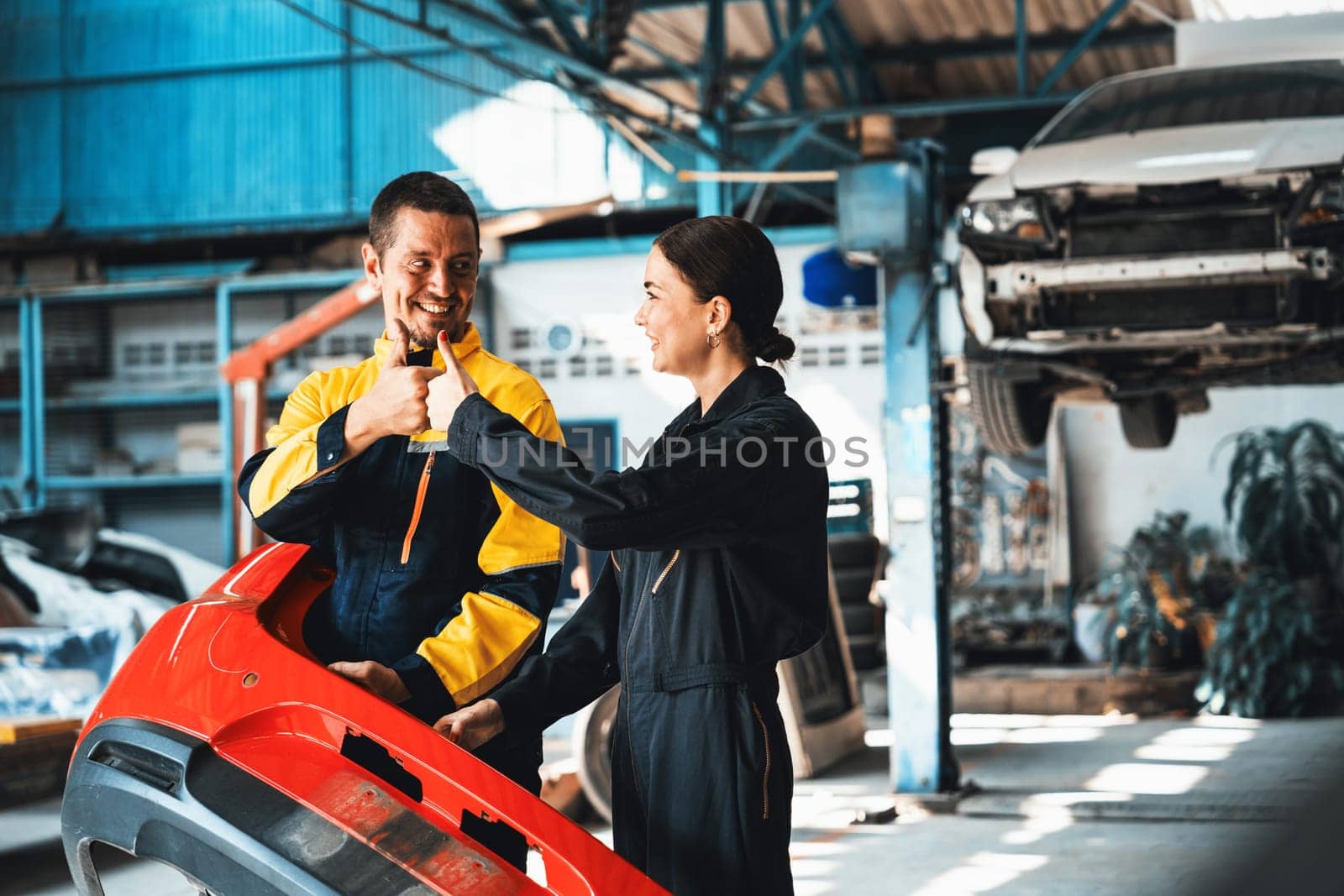 Two happy vehicle mechanic celebrate and high five after made successful car inspection or repair in automotive service car workshop. Technician team enjoy accomplishment together in garage. Oxus