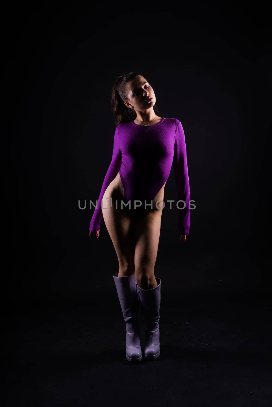 Seductive young female in violet bodysuit on dark and red background by Zelenin