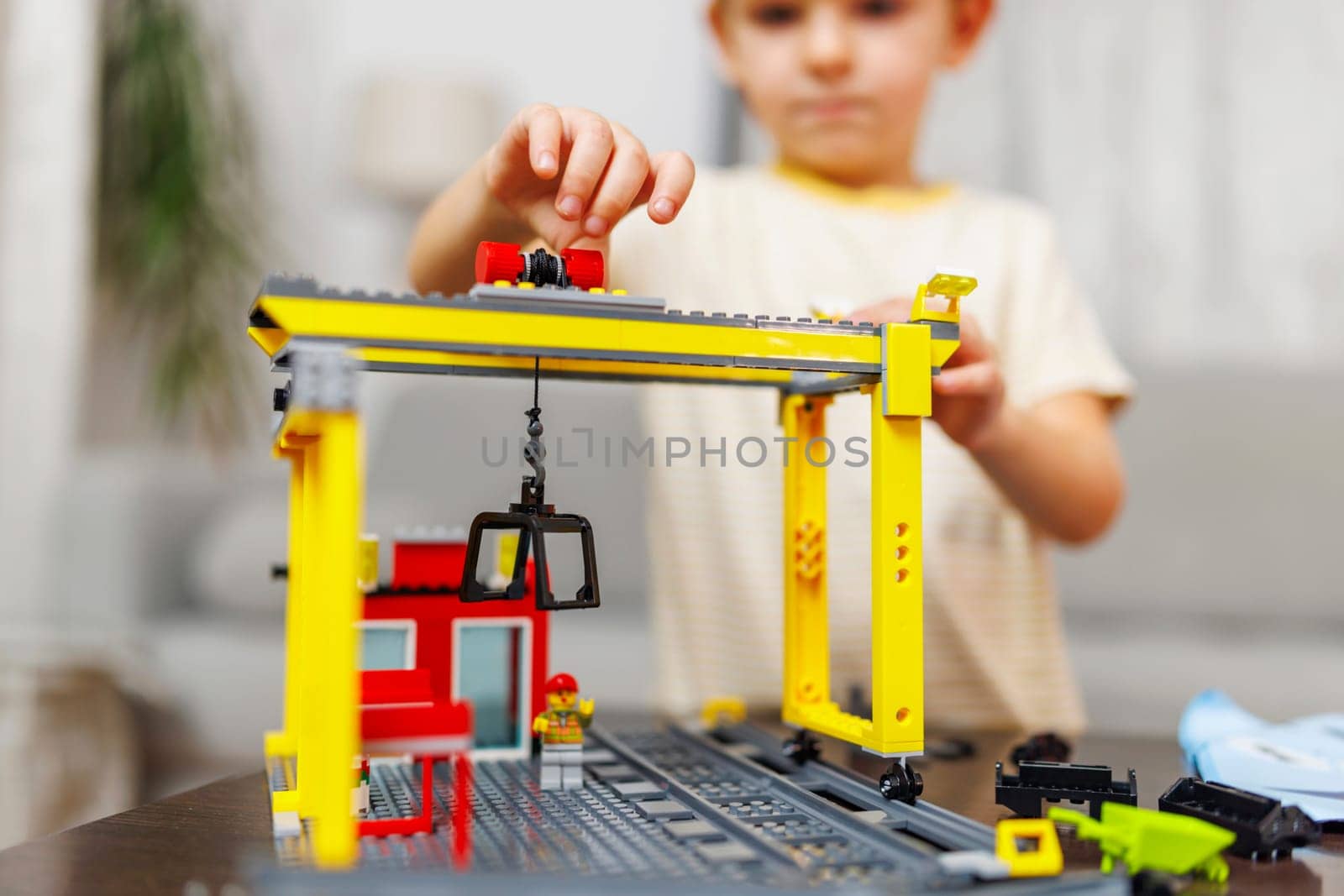 Child boy playing and building with colorful plastic bricks at the table. Early learning and development