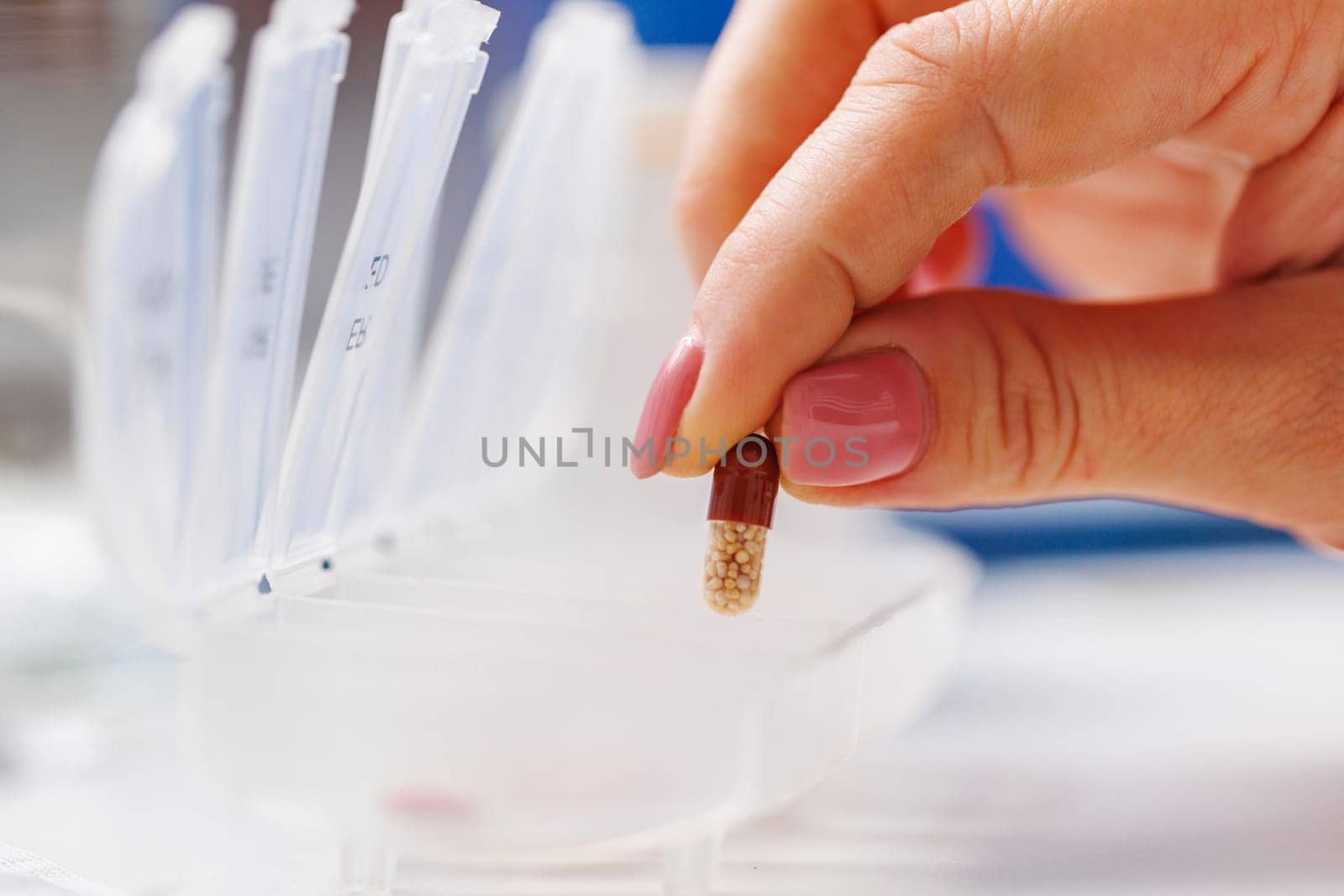 Woman hand putting pills into open pill organizer or plastic pillbox. Sorting of tablets for daily use according to a doctor's prescription