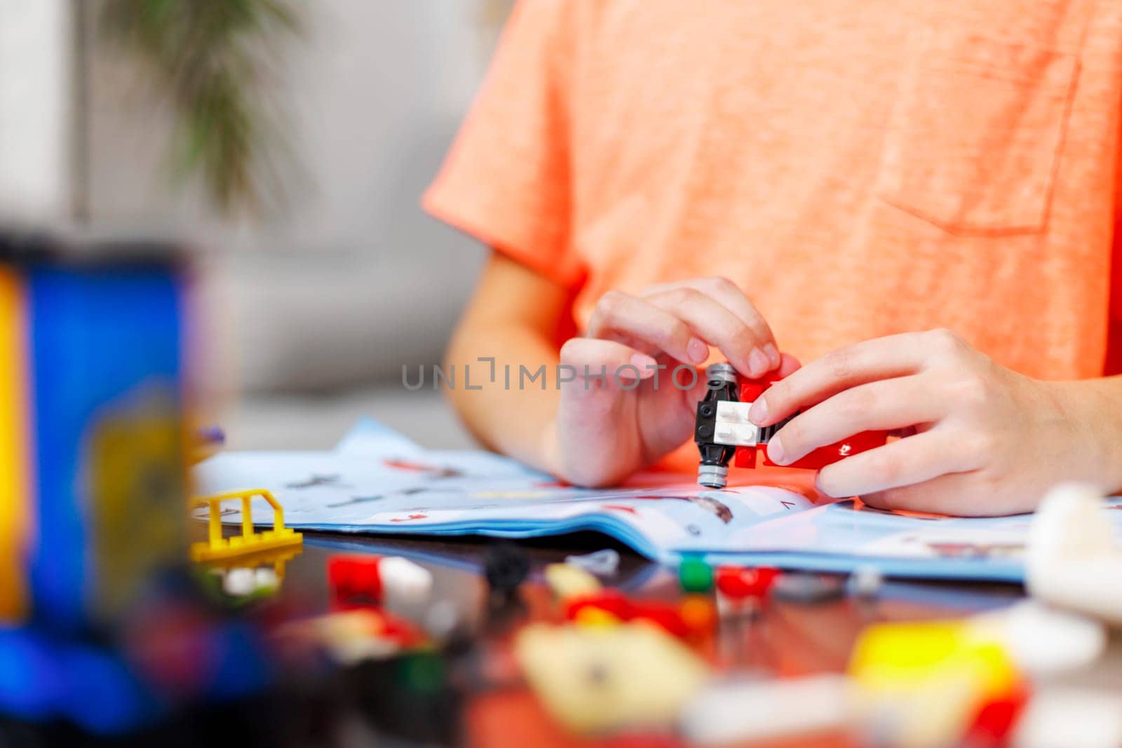 Child boy playing and building with colorful plastic bricks at the table. Early learning and development