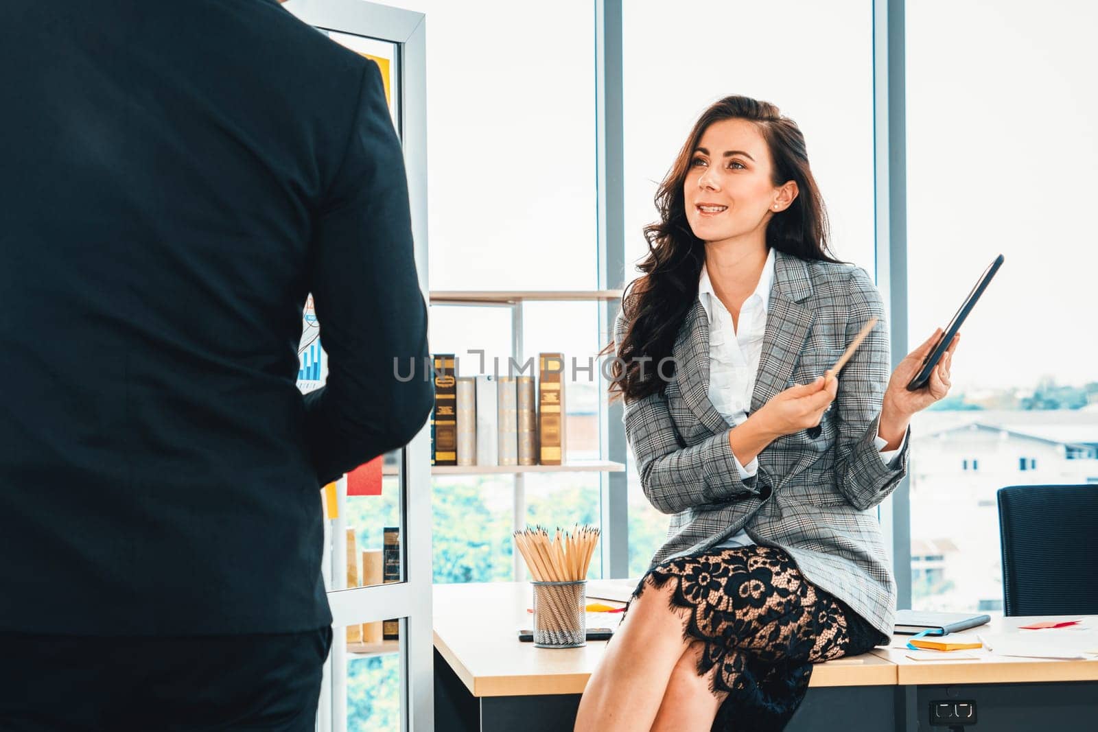 Two business people talk project strategy at office meeting room. Businessman discuss project planning with colleague at modern workplace while having conversation and advice on financial report. Jivy