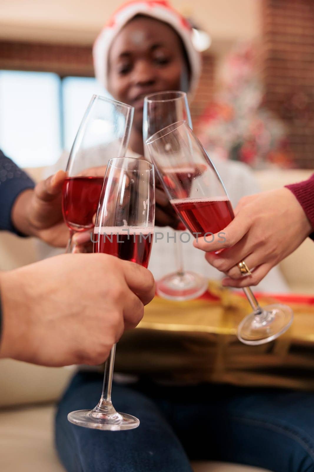 Coworkers celebrating christmas in office and clinking glasses of sparkling wine closeup. Cheerful company employees hands holding alcohol drink and toasting to new year holiday